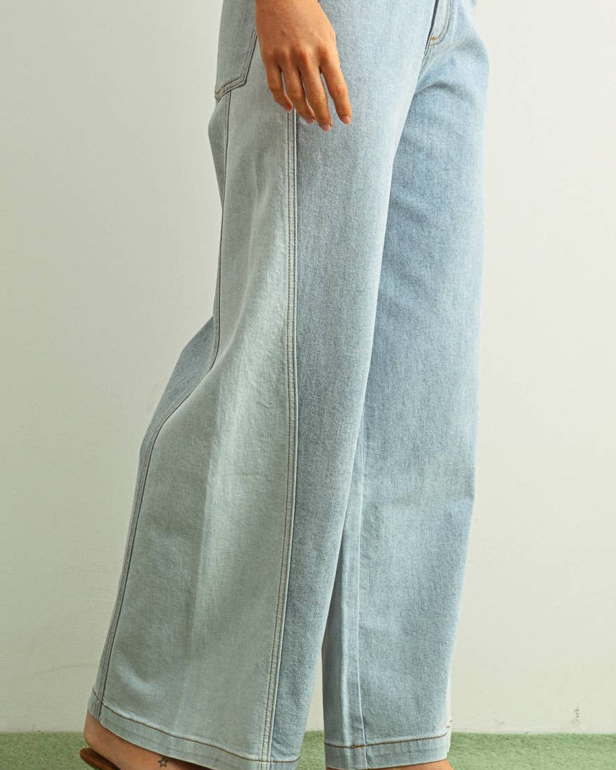Woman wearing light denim jeans and light brown shoes standing behind a white background