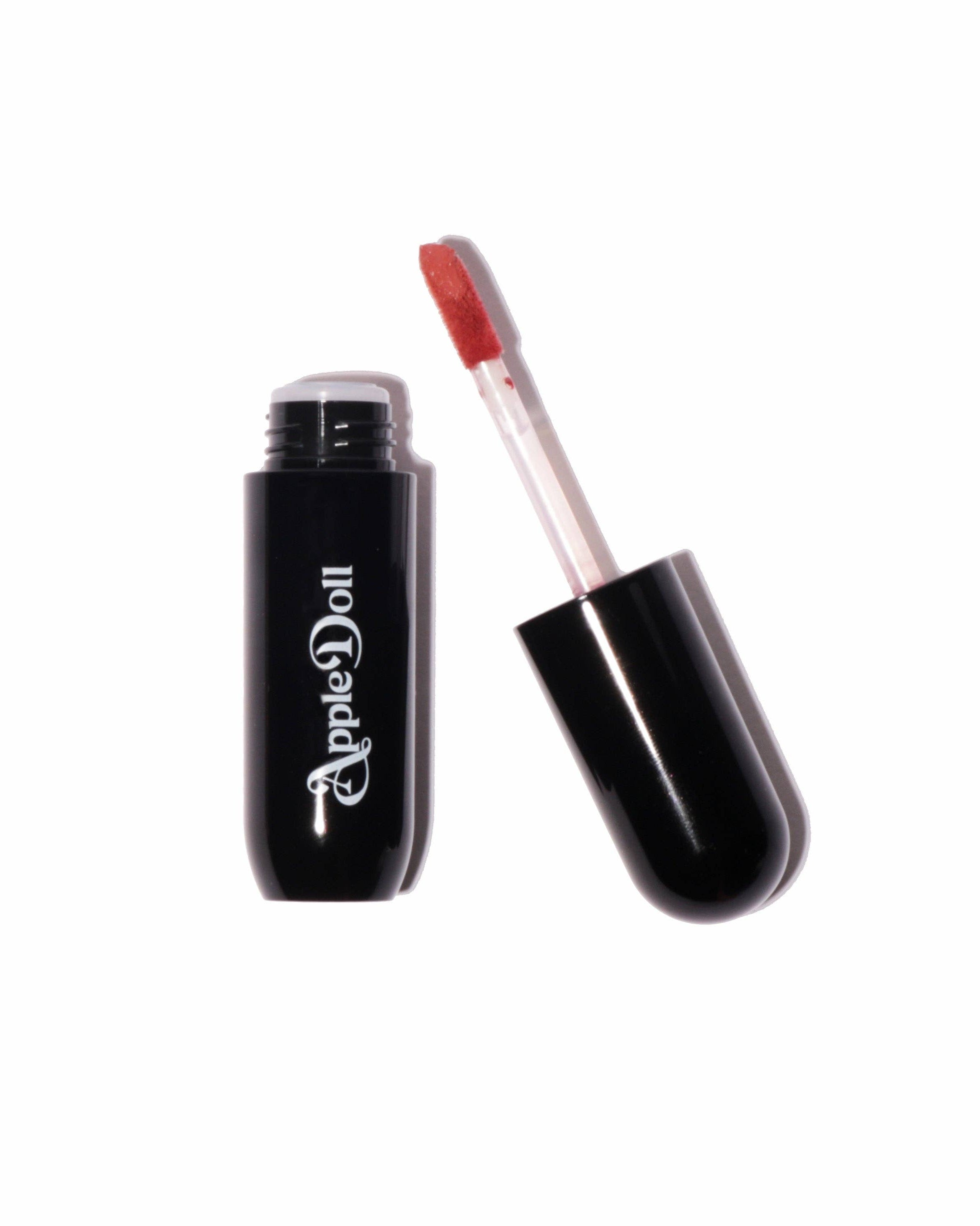 Black lip gloss with red applicator on a white background