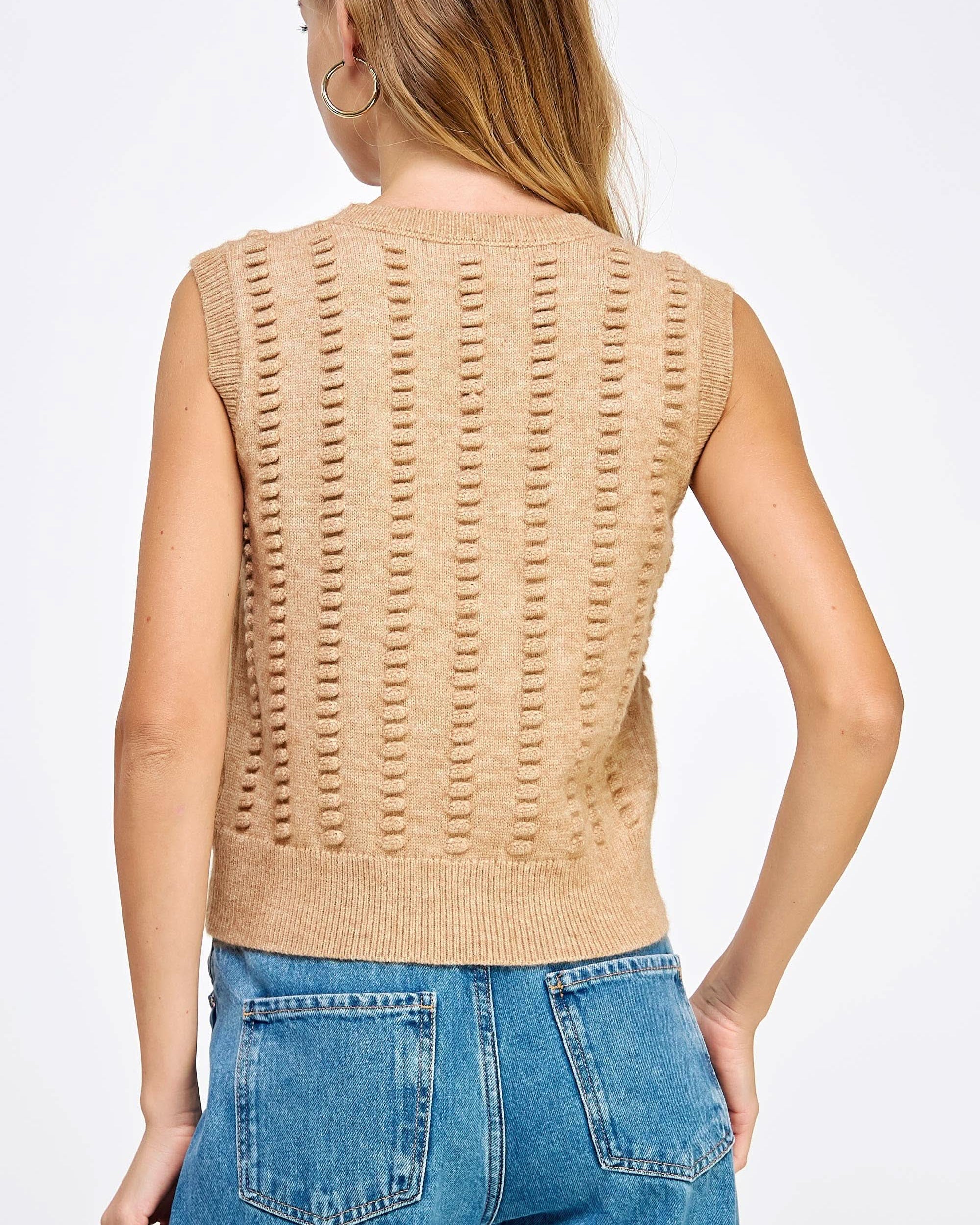 Woman wearing tan textured sweater vest with black shorts