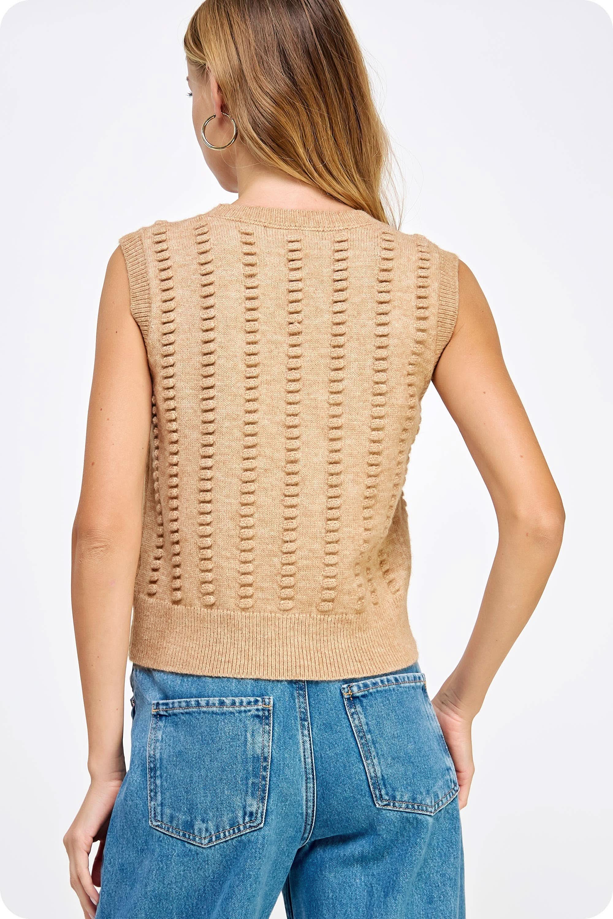 Woman wearing tan textured sweater vest with black shorts