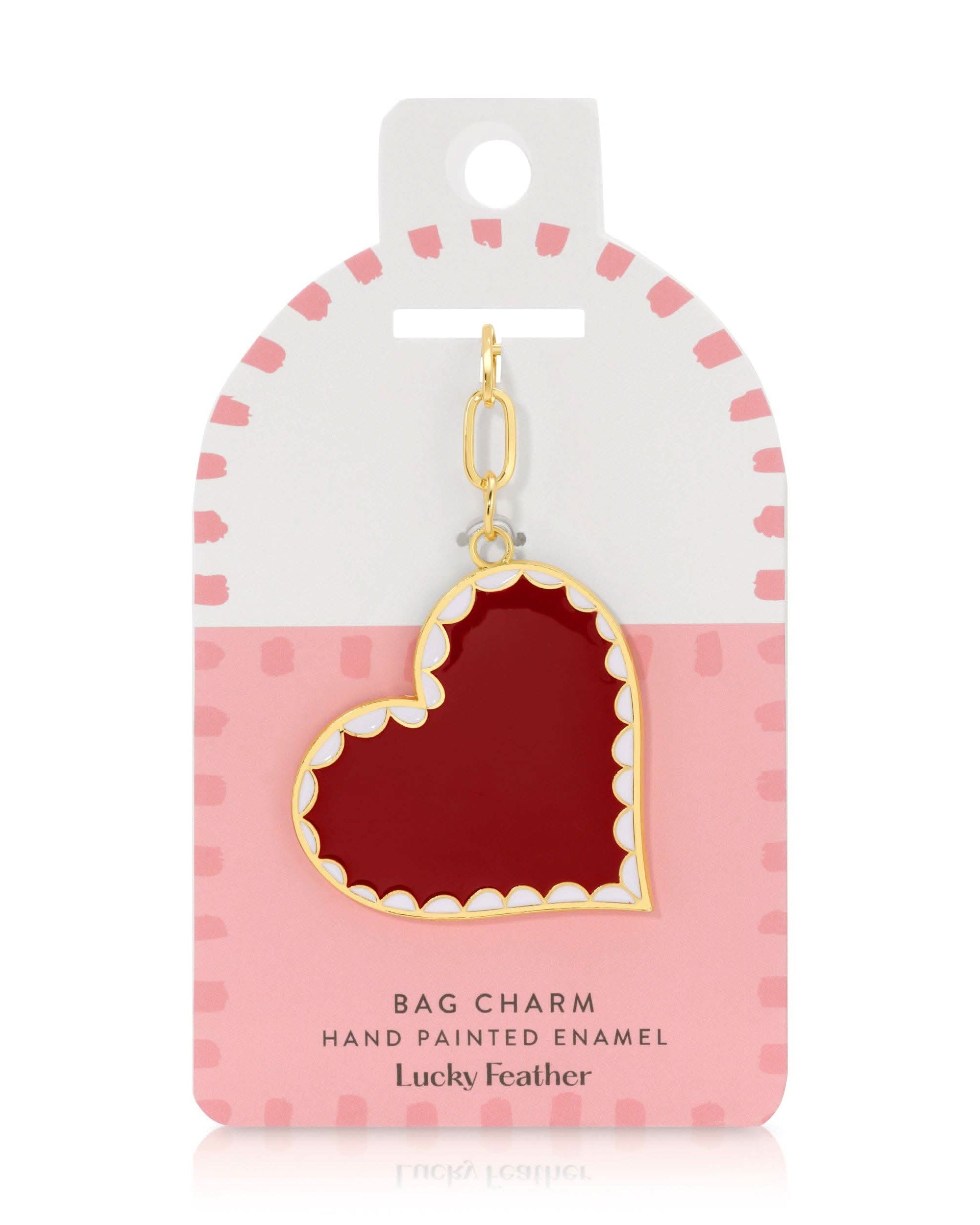 Hand painted enamel red heart bag charm with scalloped white and gold outline detail in pink and white case