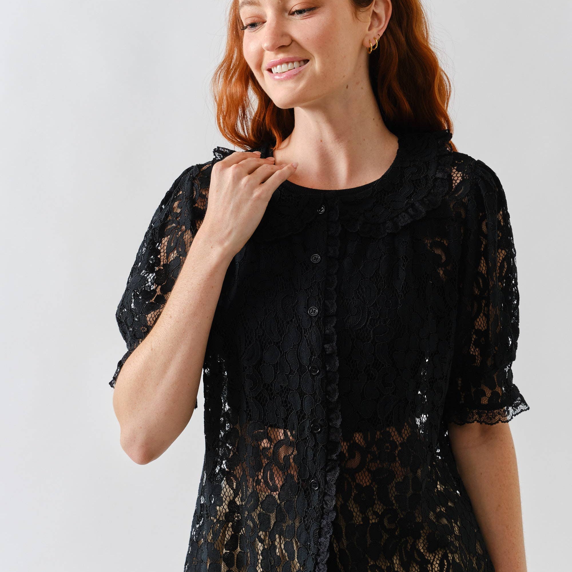 Woman wearing black lace button up blouse with beige bottoms