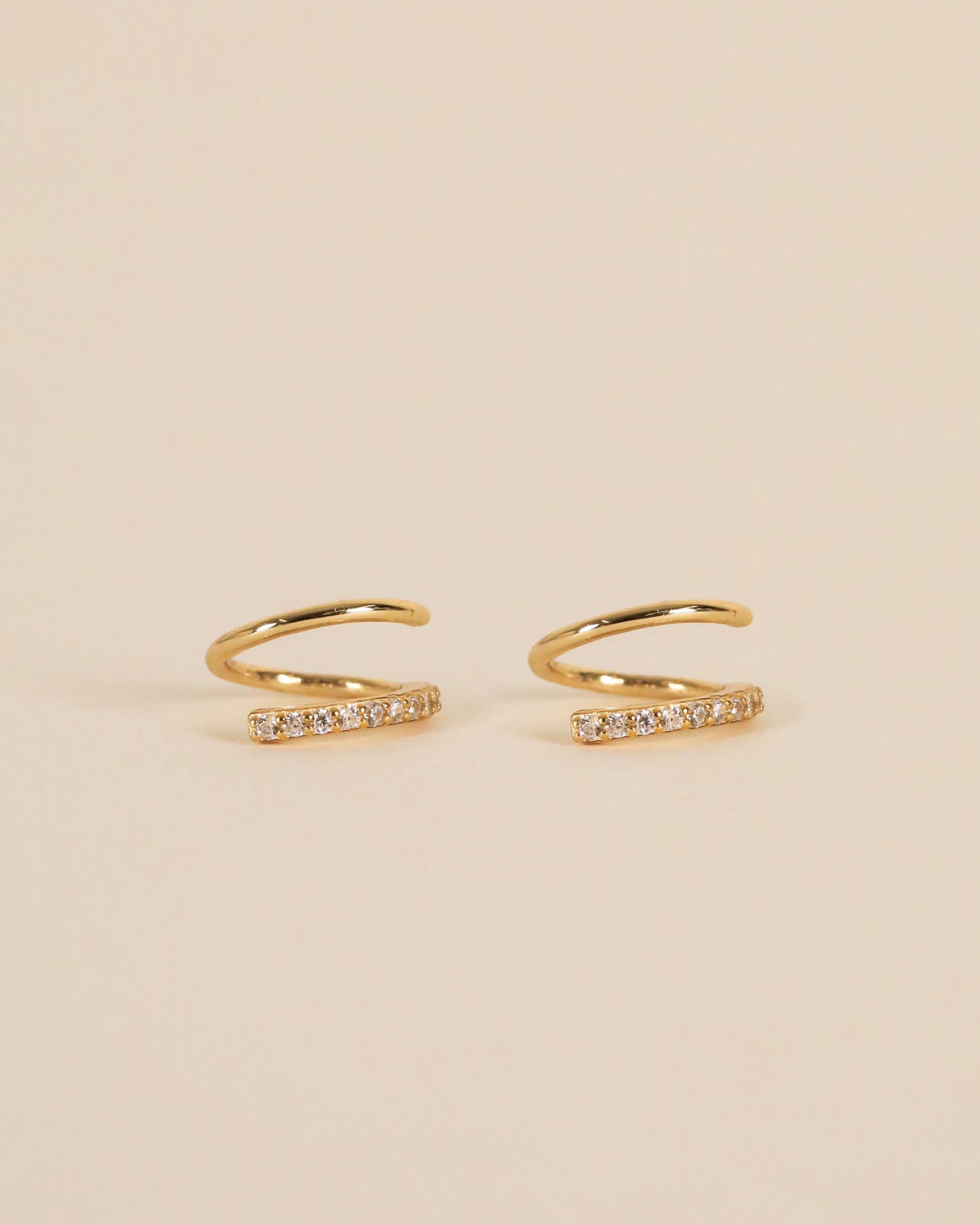 Gold pave spiral earrings from Jaxkelly sitting against cream background