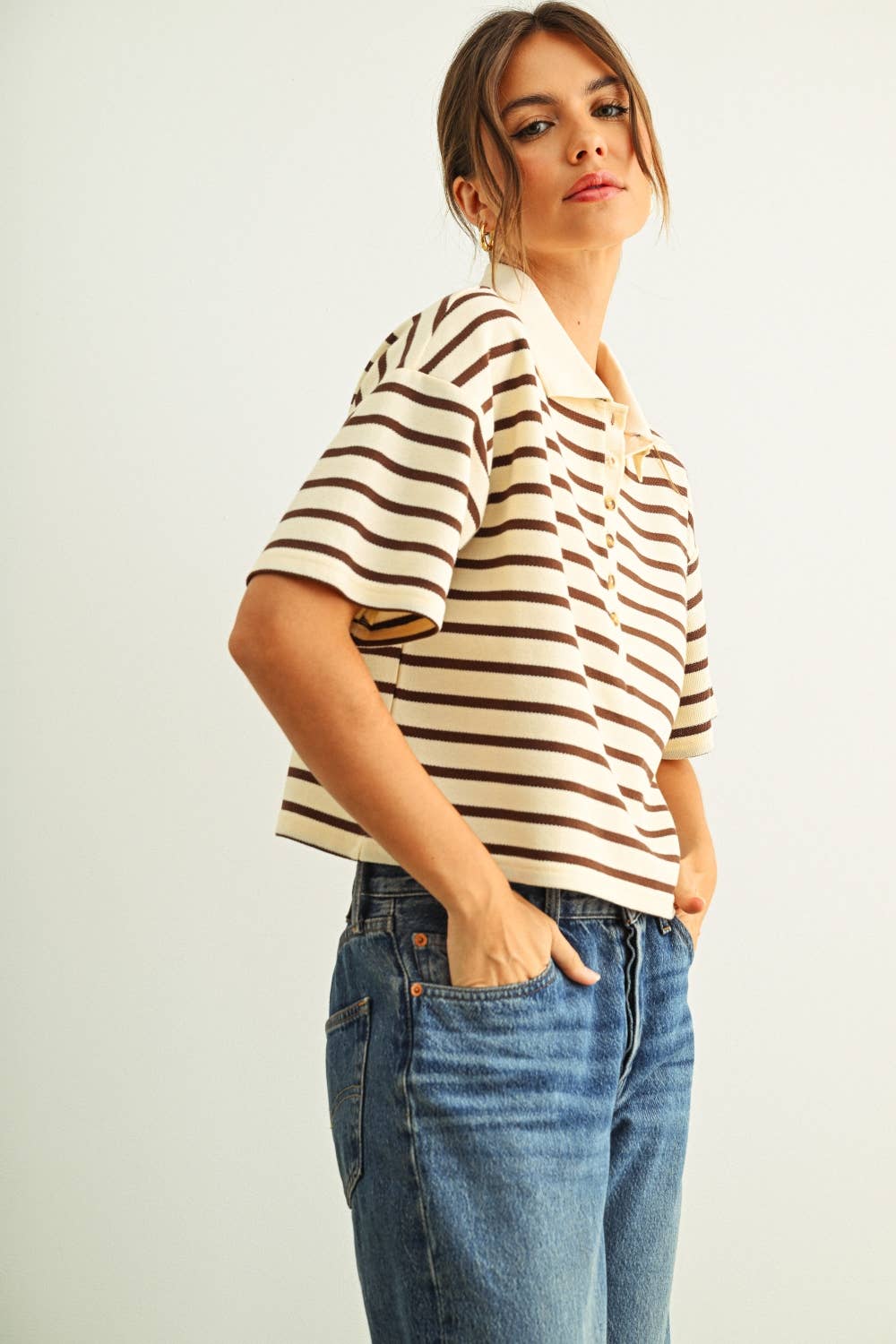 Woman wearing a striped shirt and jeans against a plain background
