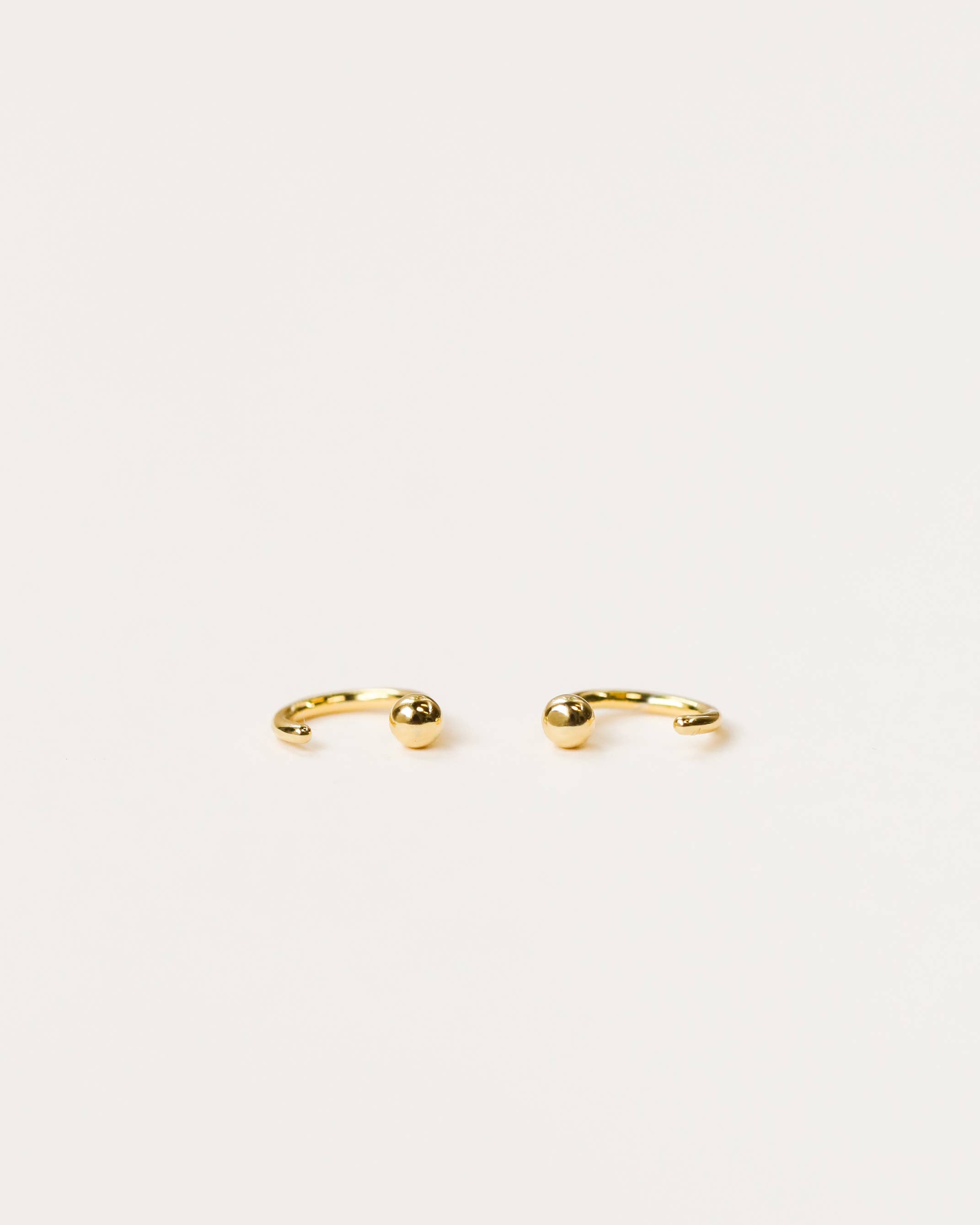 Gold earrings on a light beige background
