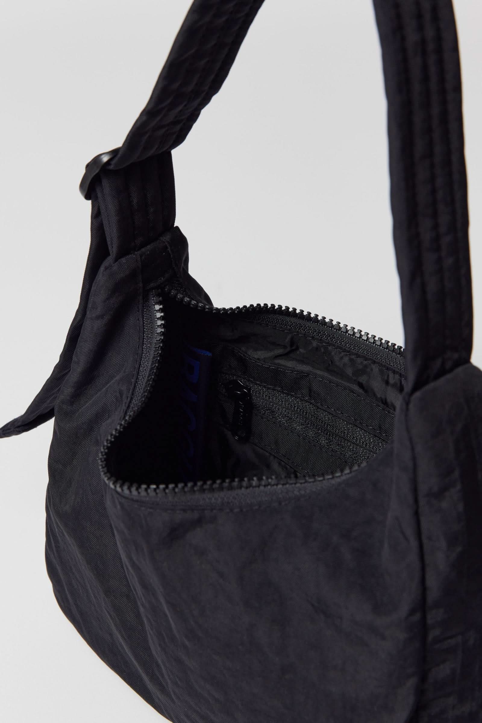 inside details of black nylon shoulder bag from BAGGU sitting on white background