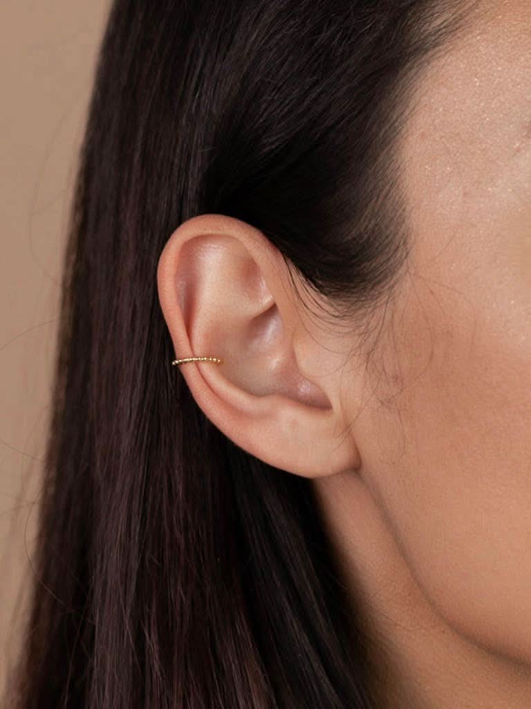 woman wearing gold ball earing cuff