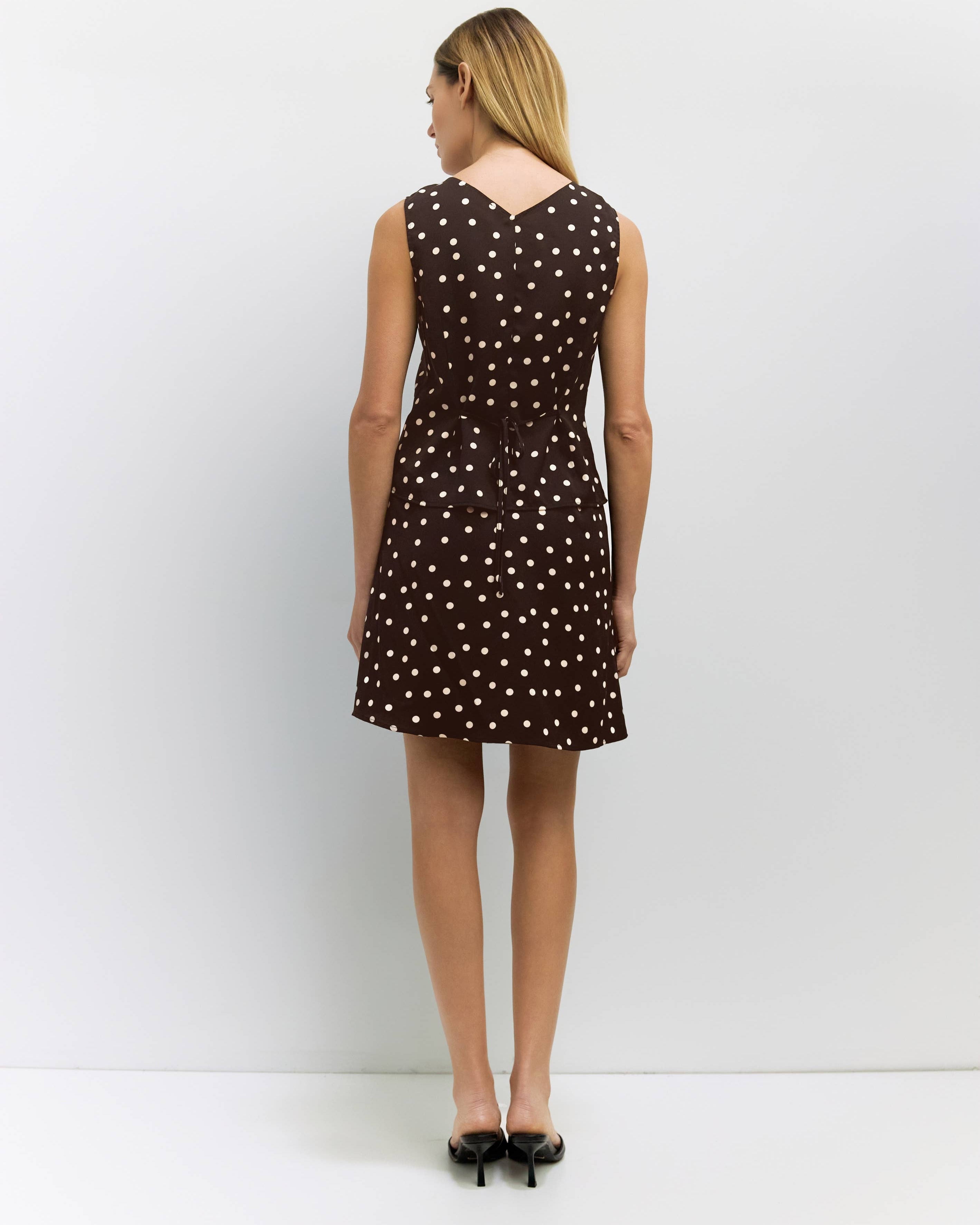 Woman wearing a brown top and skirt with white polka dots against a white background