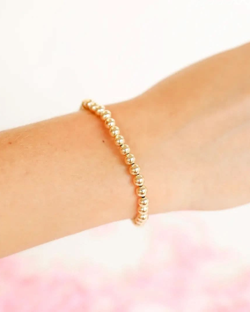 14K Gold Filled Gold beaded bracelet on a wrist with a soft pink