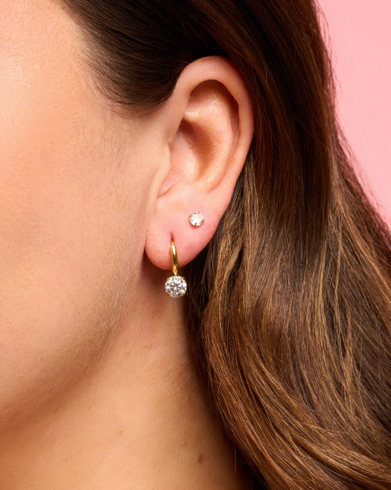 Woman wearing Gold huggie earrings with gem dangle detail