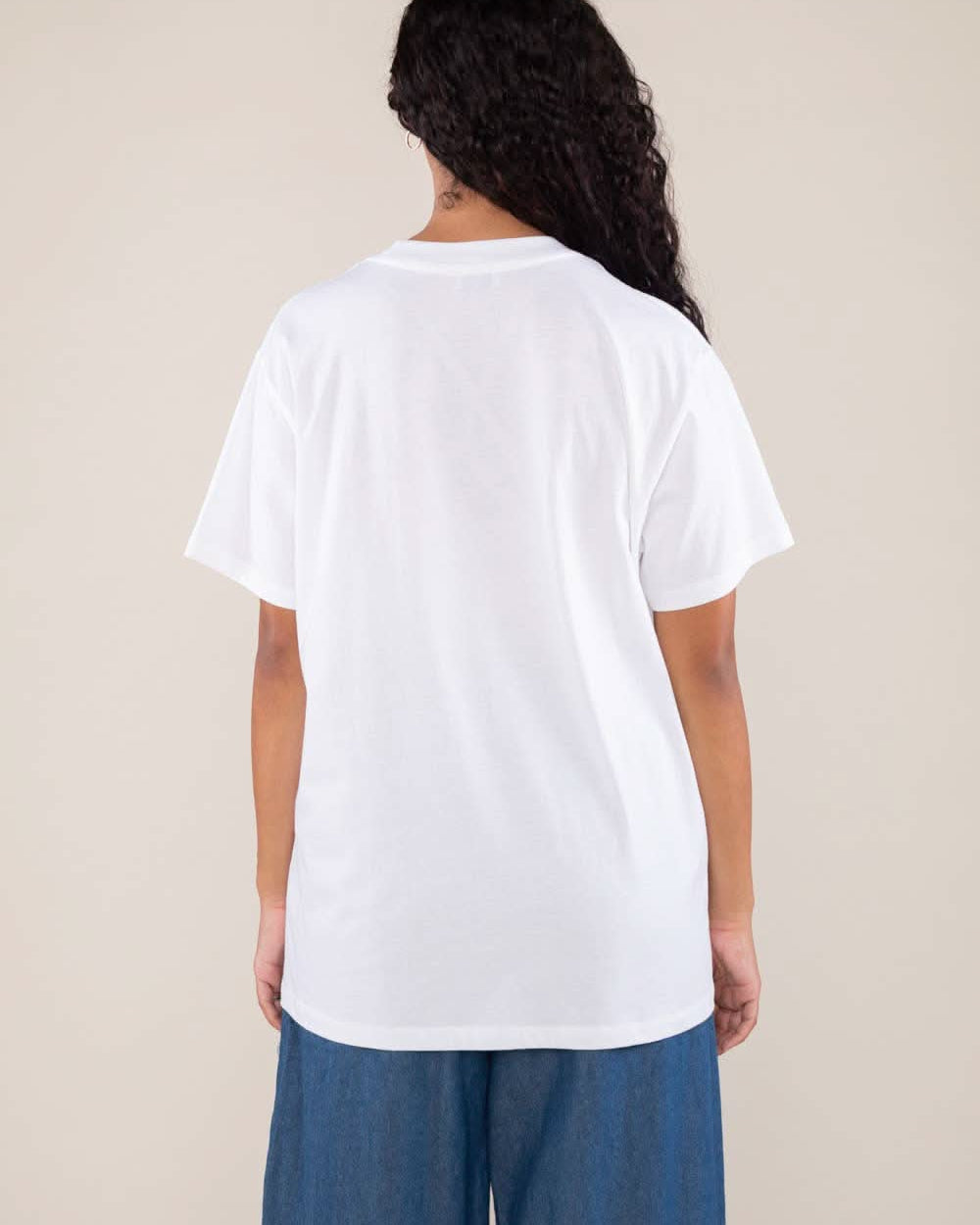 Woman wearing white boxy, oversized, shirt sleeved, tee t-shirt and jeans