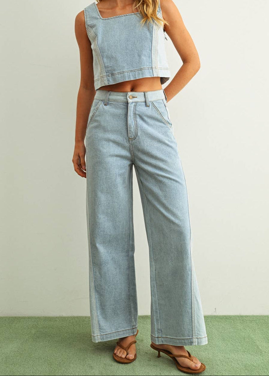 Woman wearing light denim jeans and light denim top standing behind a white background