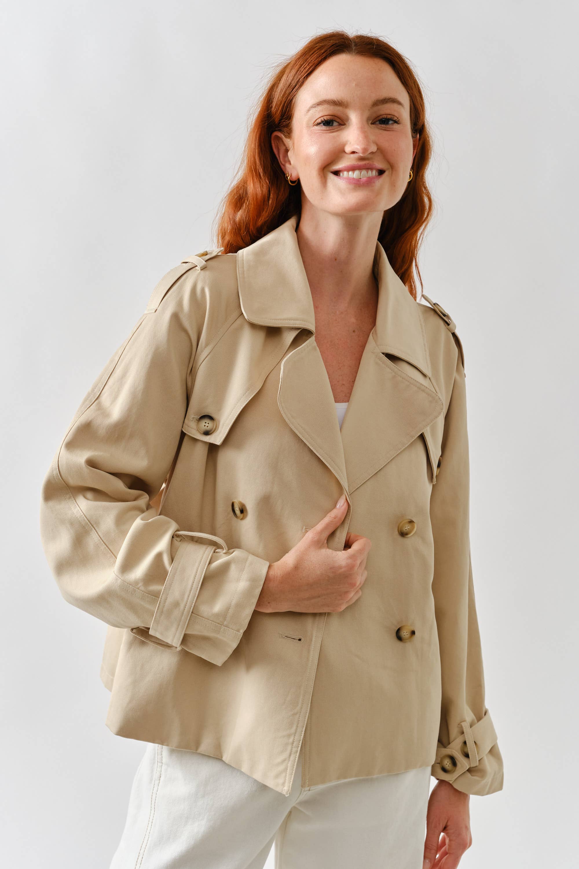 Woman wearing a beige trench coat against a white background
