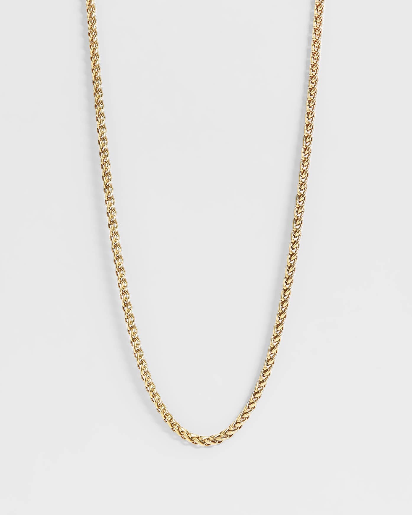 Gold chain necklace on a light gray background