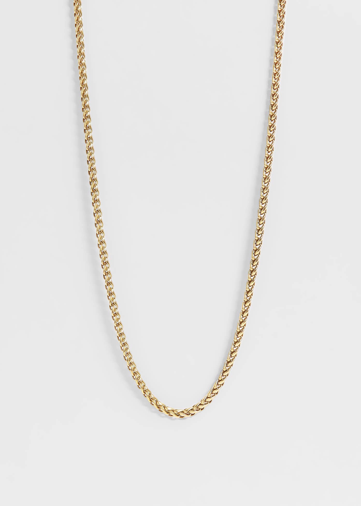 Gold chain necklace on a light gray background
