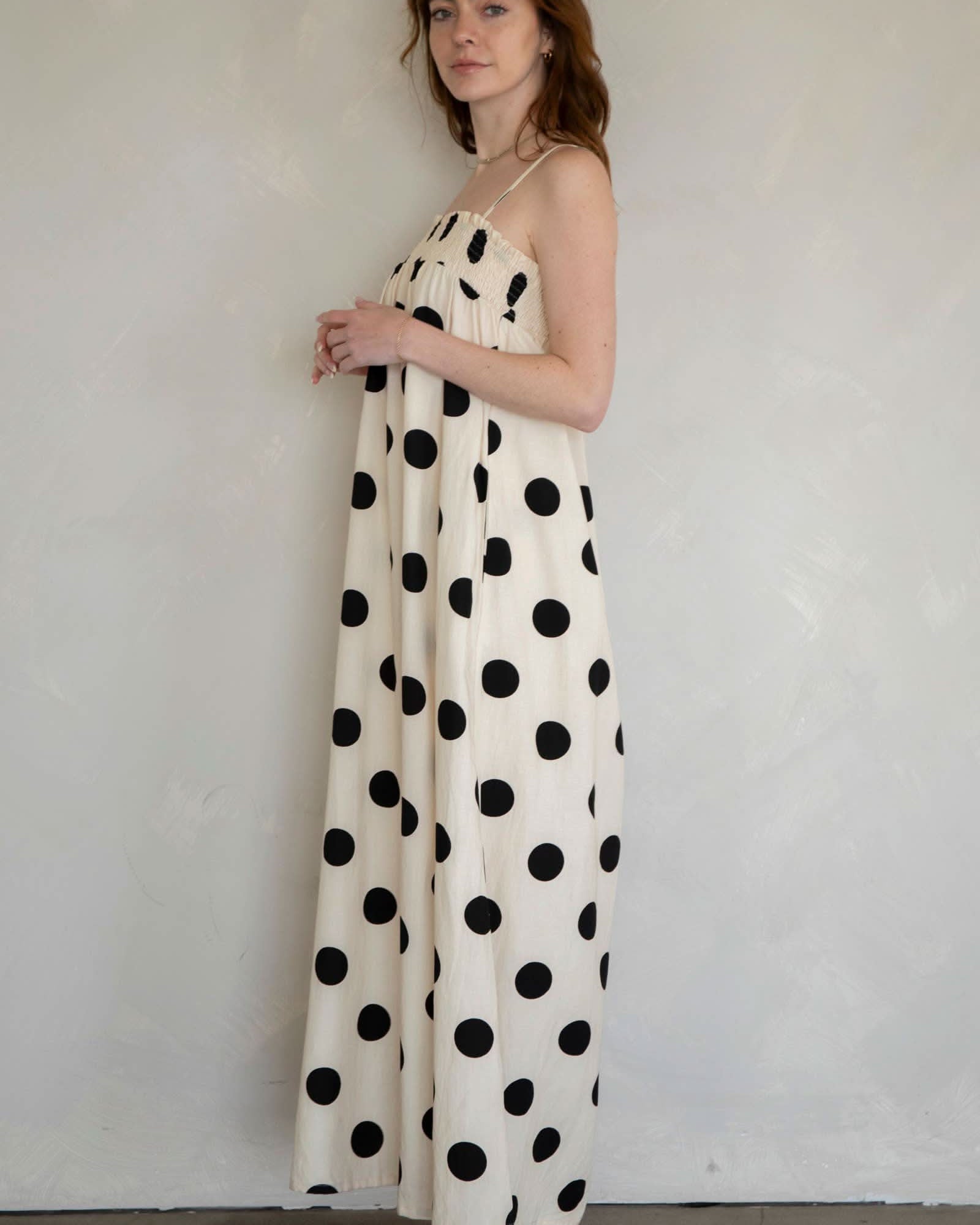 Woman wearing a long polka dot dress against a plain background