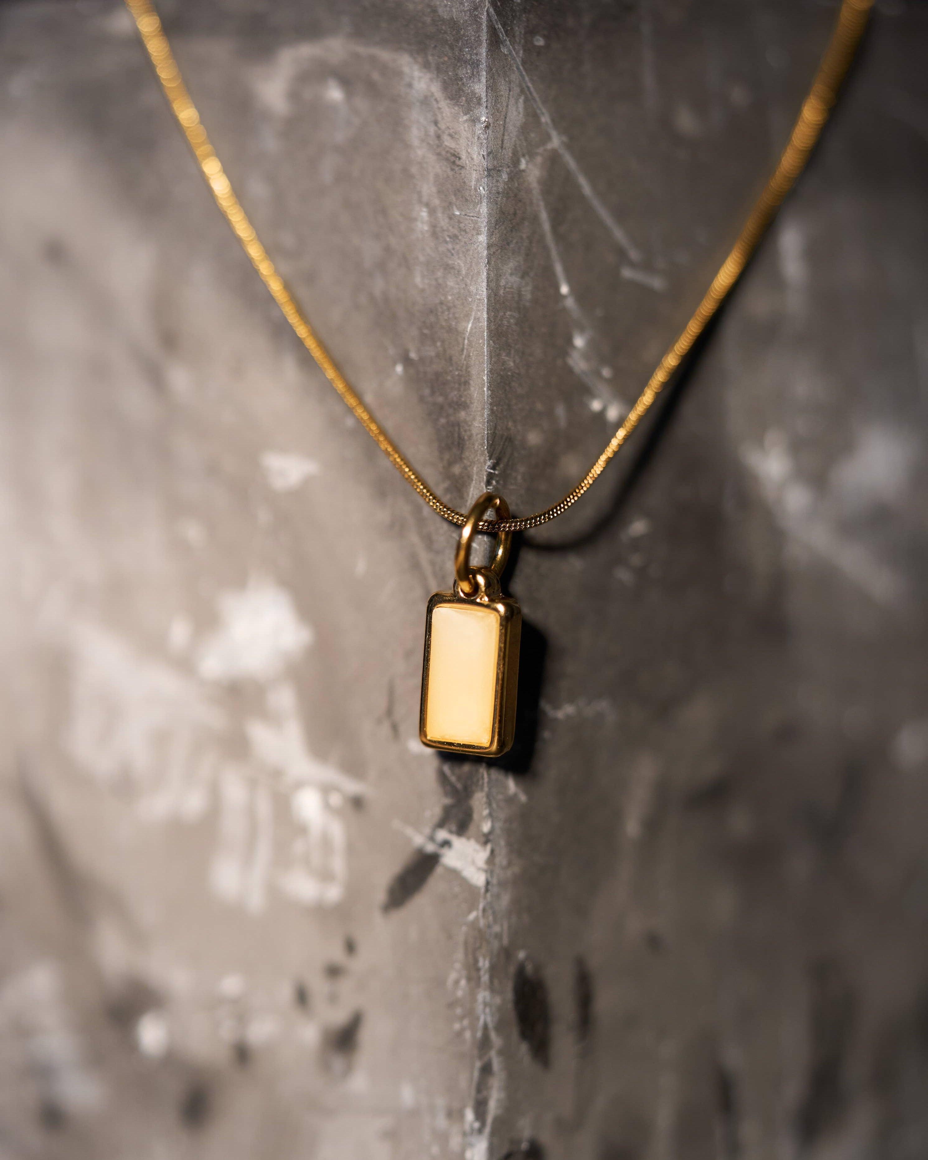 Gold necklace with a rectangular cream-colored pendant
