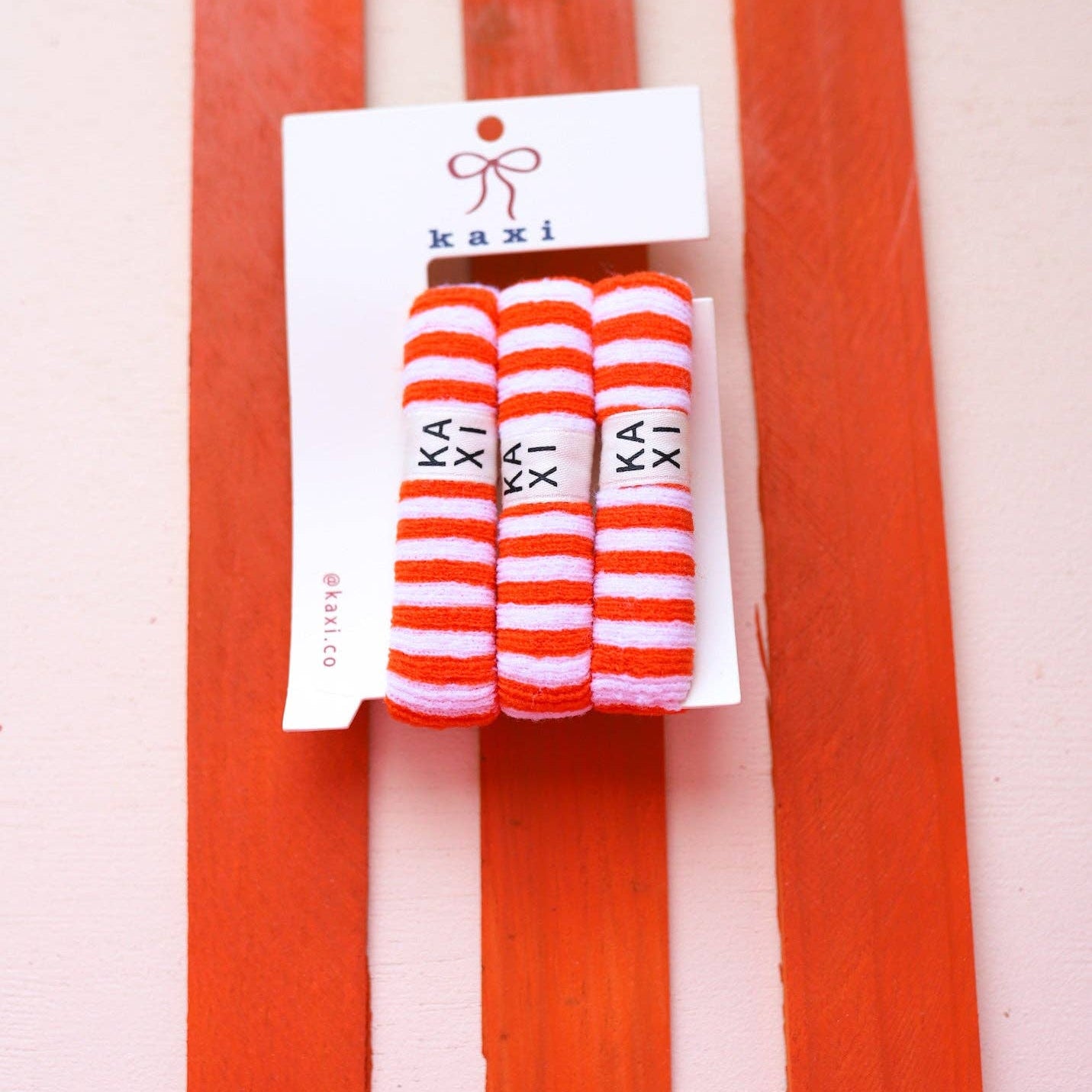 Pack of striped socks with 'kaki' branding on a red and white striped background