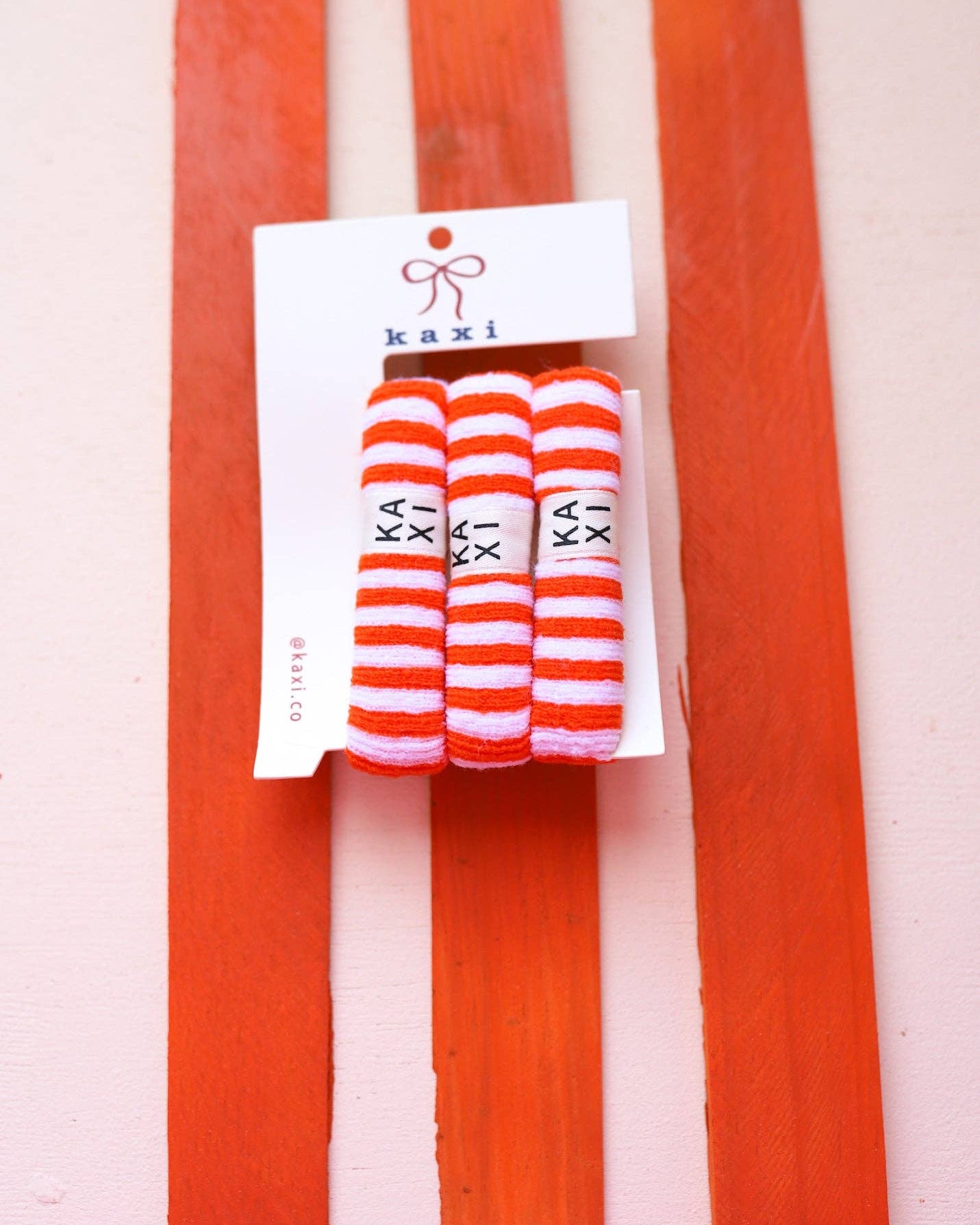 Pack of striped socks with 'kaki' branding on a red and white striped background