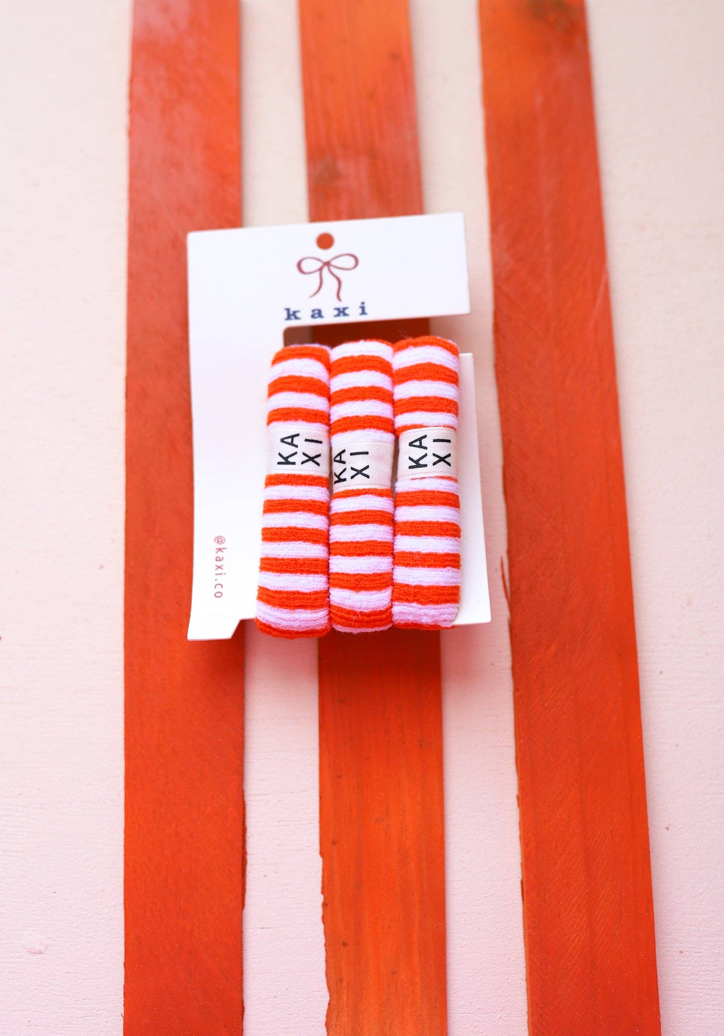 Pack of striped socks with 'kaki' branding on a red and white striped background