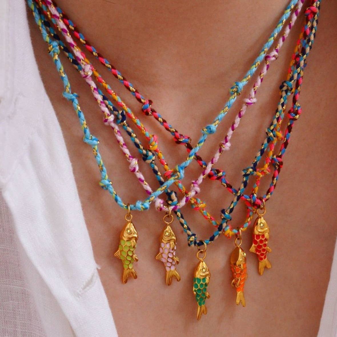 Colorful braided necklace with fish pendants on a person's neck