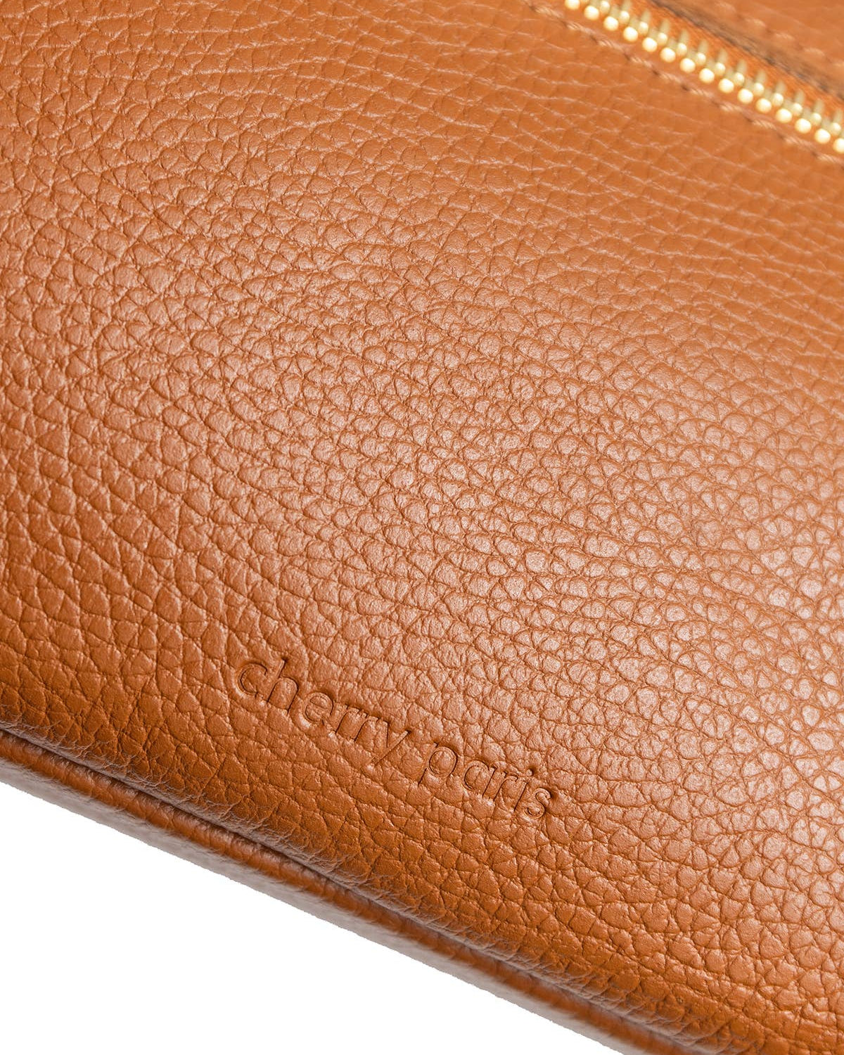Close-up of a tan pebbled leather clutch or wallet with a gold-tone zipper and debossed 'chloé paris' branding, shown on a white background.