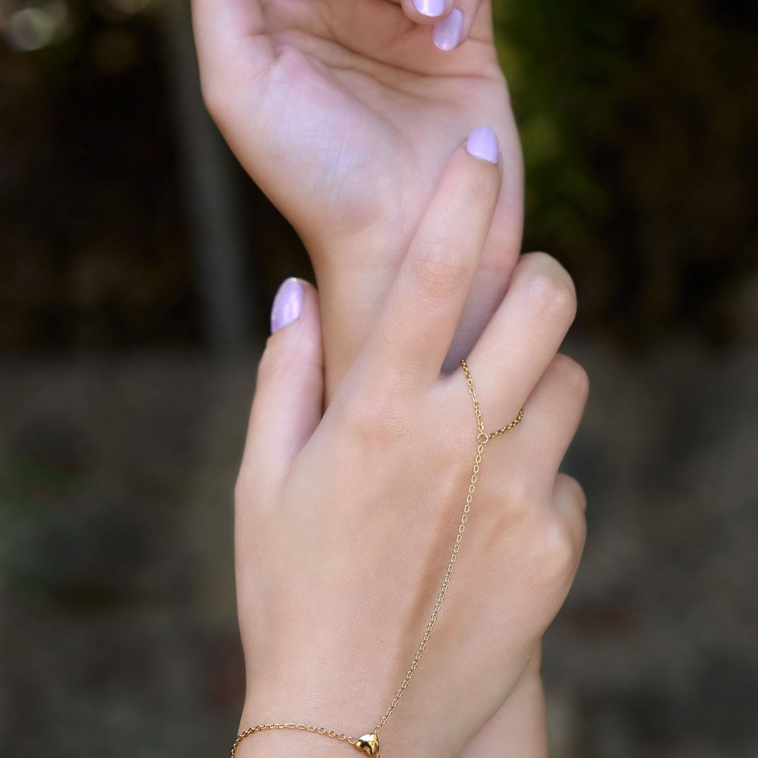 Delicate gold hand chain bracelet connected to a thin ring