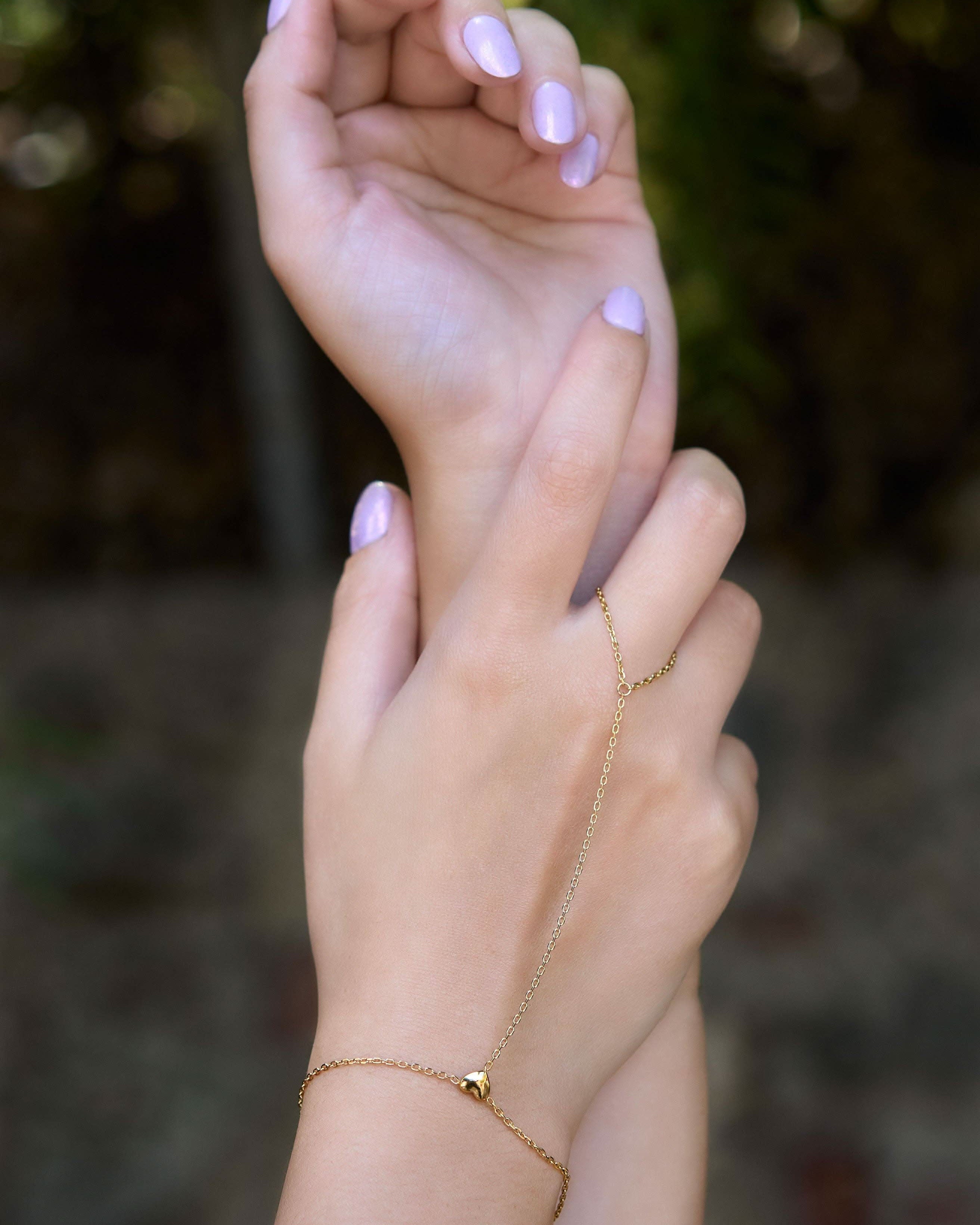 Delicate gold hand chain bracelet connected to a thin ring
