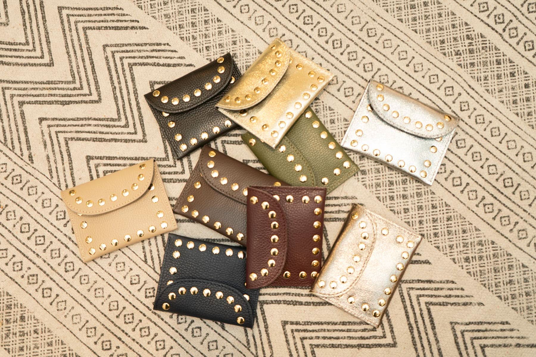 10 assorted colored flap wallet with gold embellishes outlining each wallet