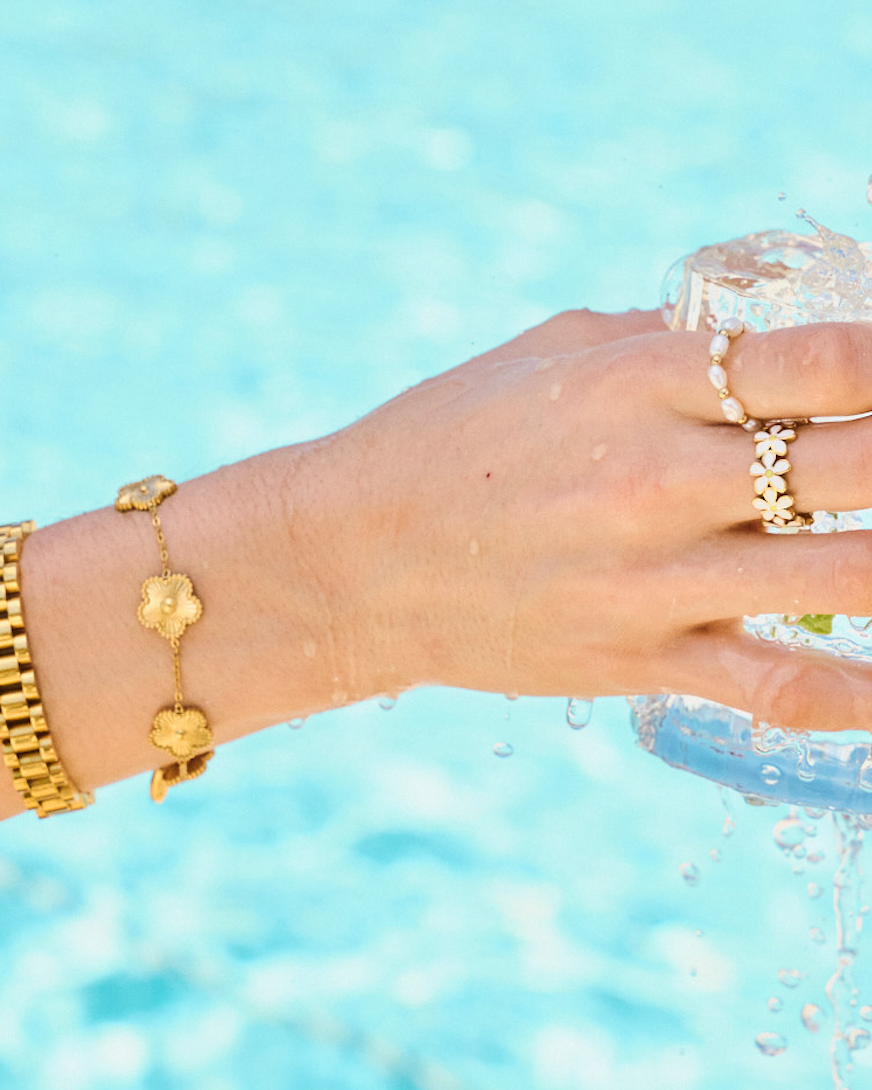 Woman wearing bracelet stack including gold watch band bracelet