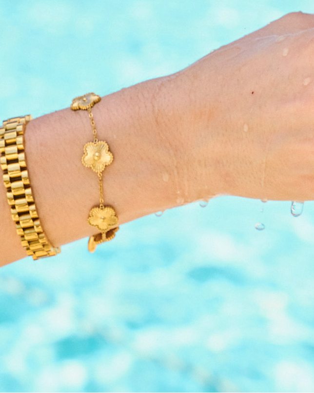 Woman wearing bracelet stack including gold watch band bracelet