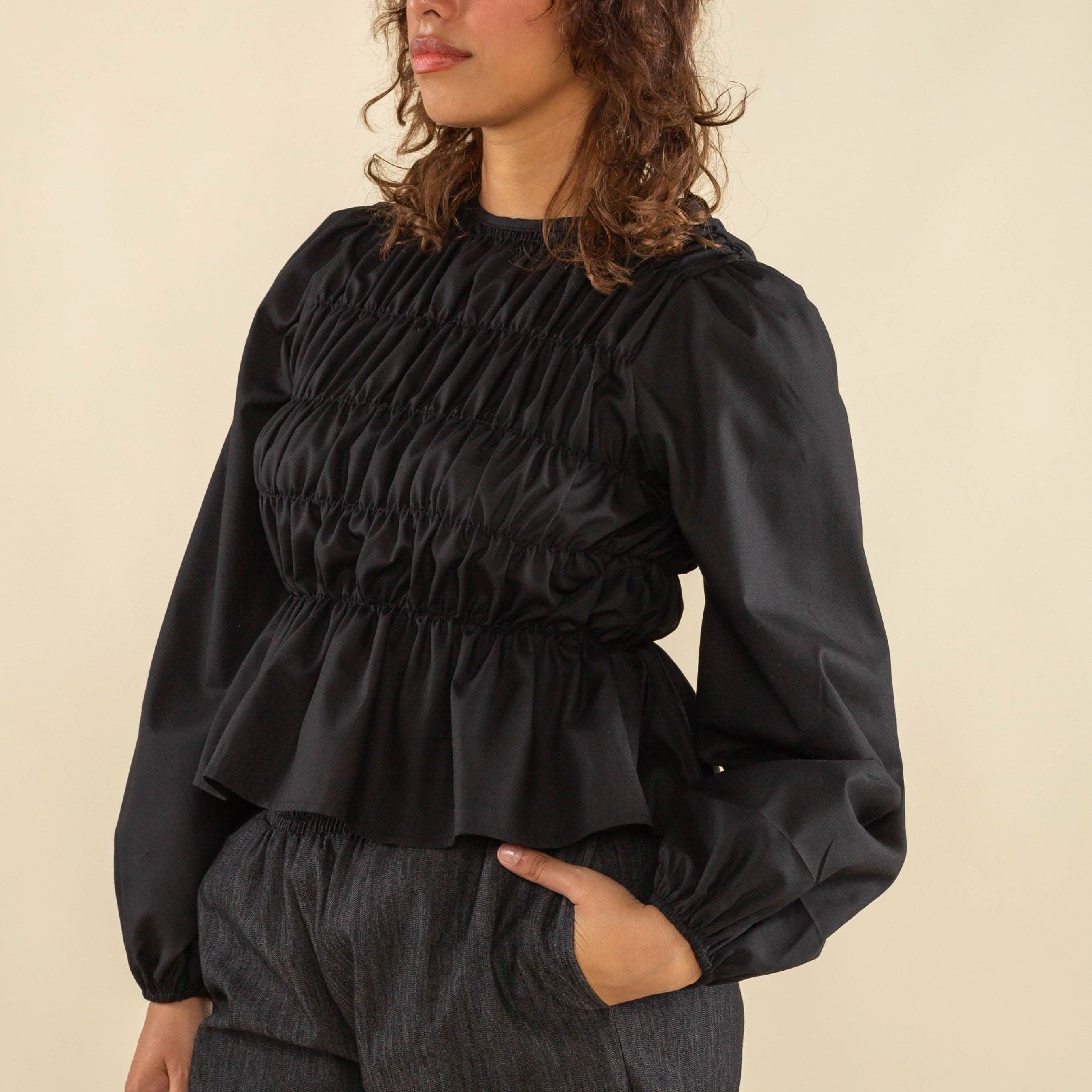 Woman wearing black, bubble long sleeve, shirred, peplum style top