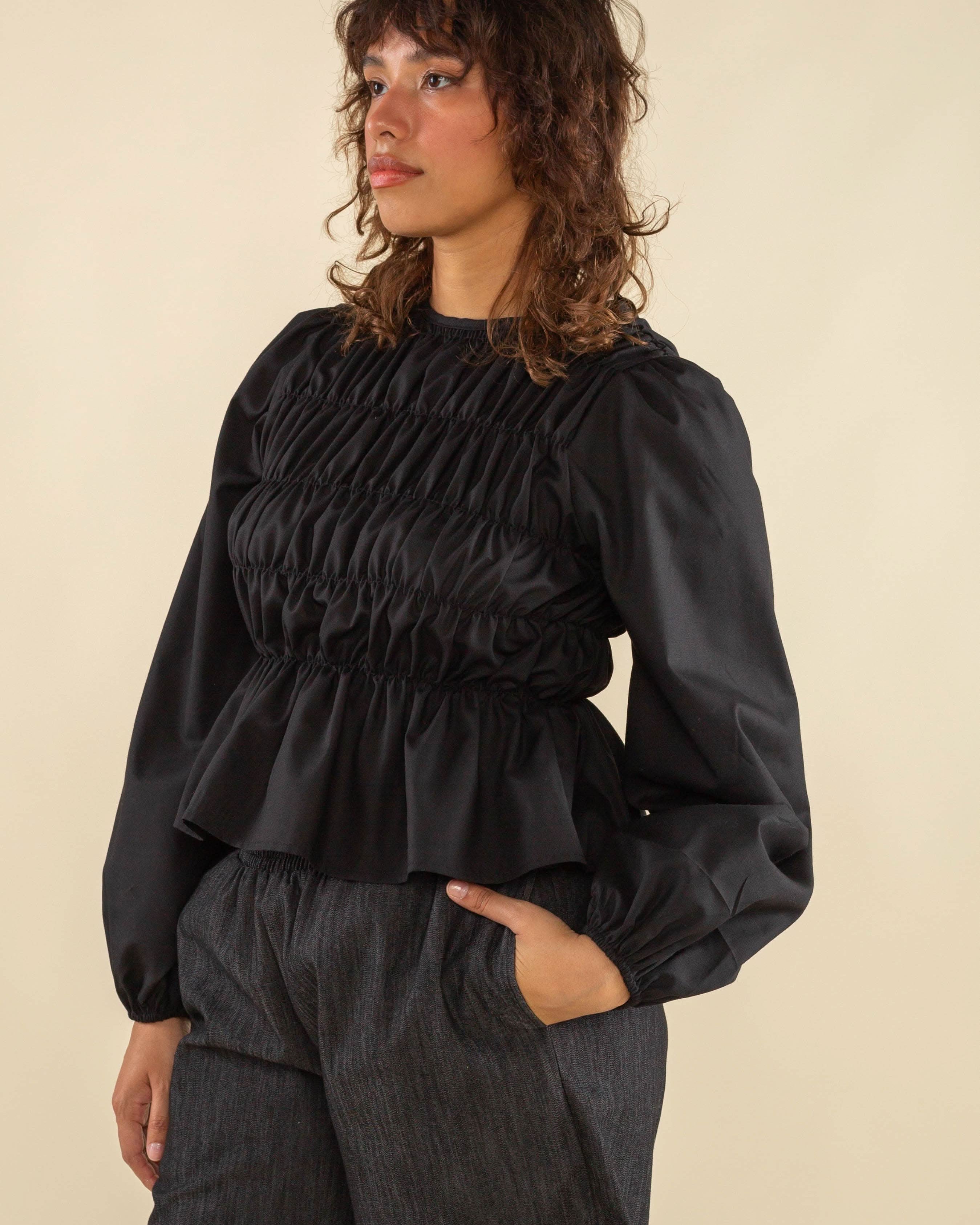 Woman wearing black, bubble long sleeve, shirred, peplum style top