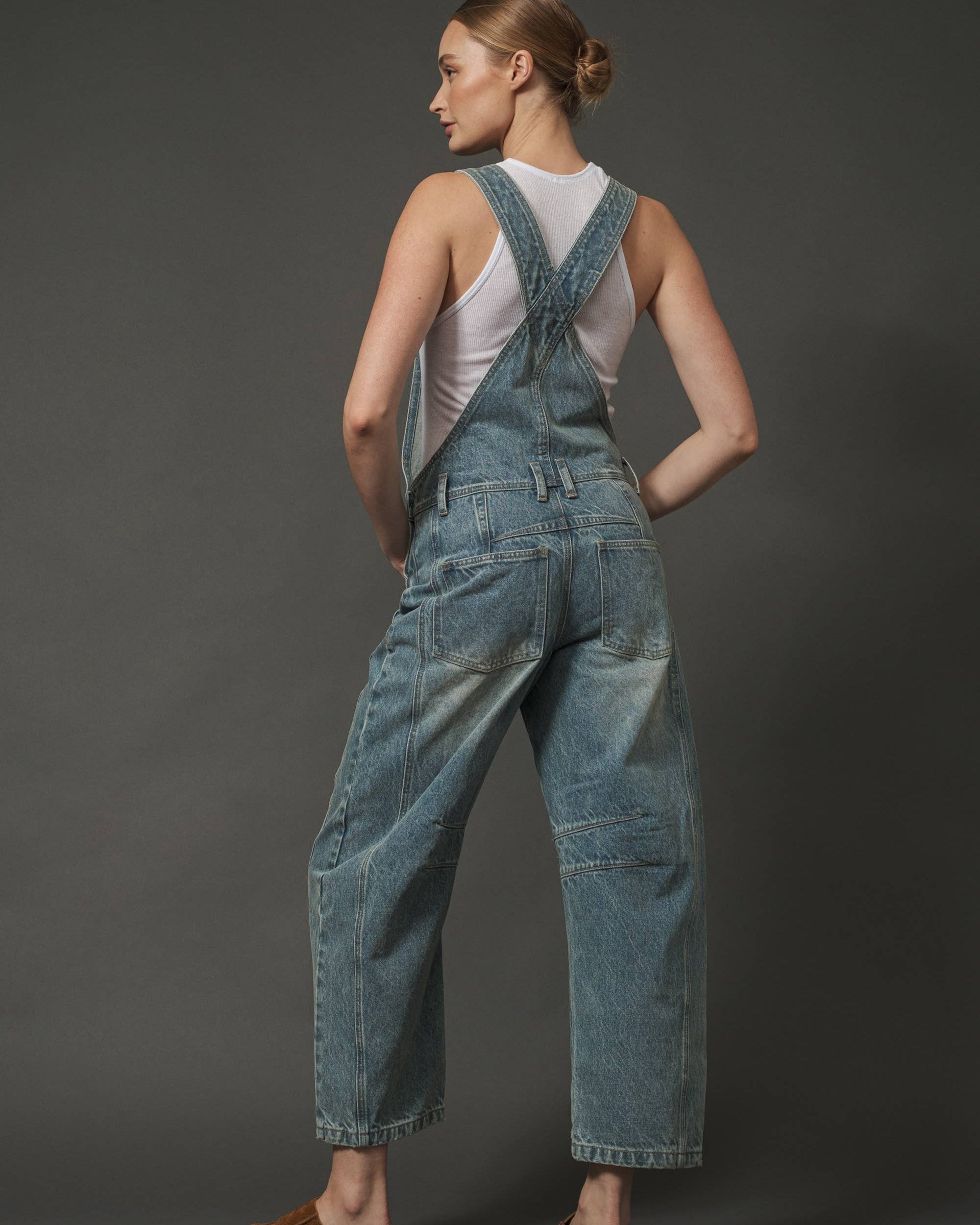 Woman wearing blue denim overalls on a dark gray background