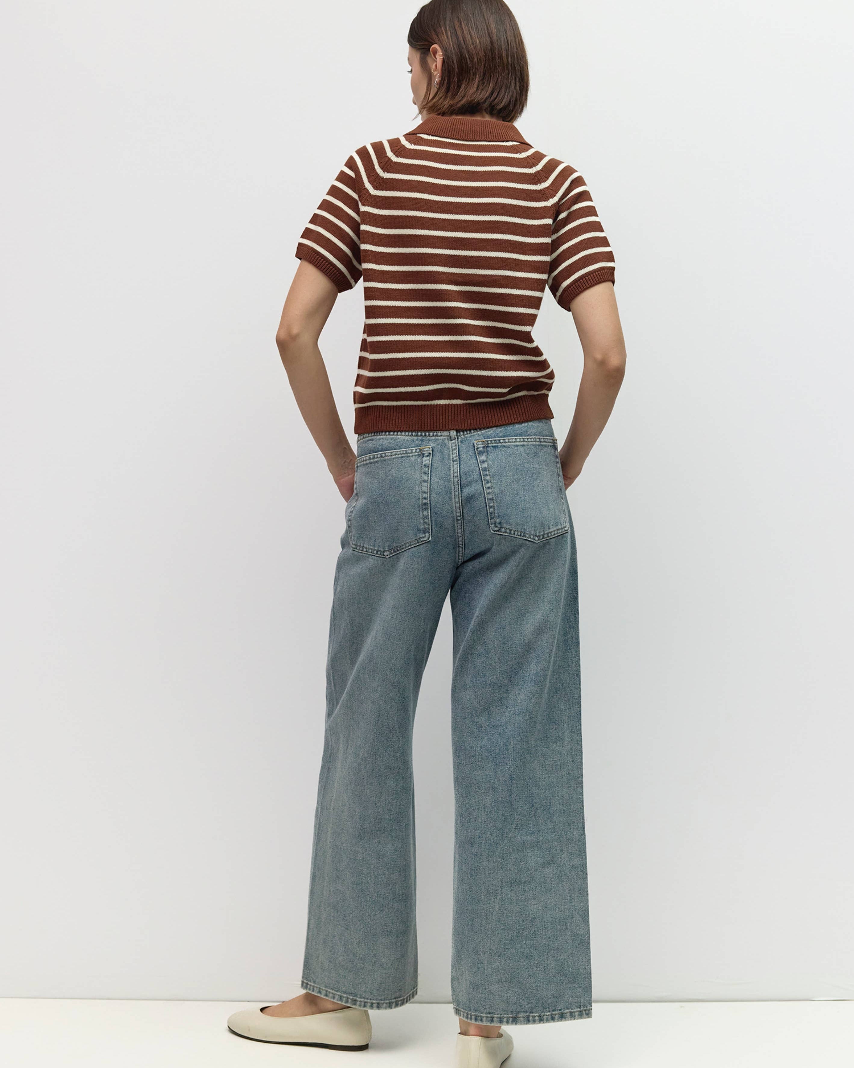 Person wearing a striped shirt and wide-leg jeans against a white background