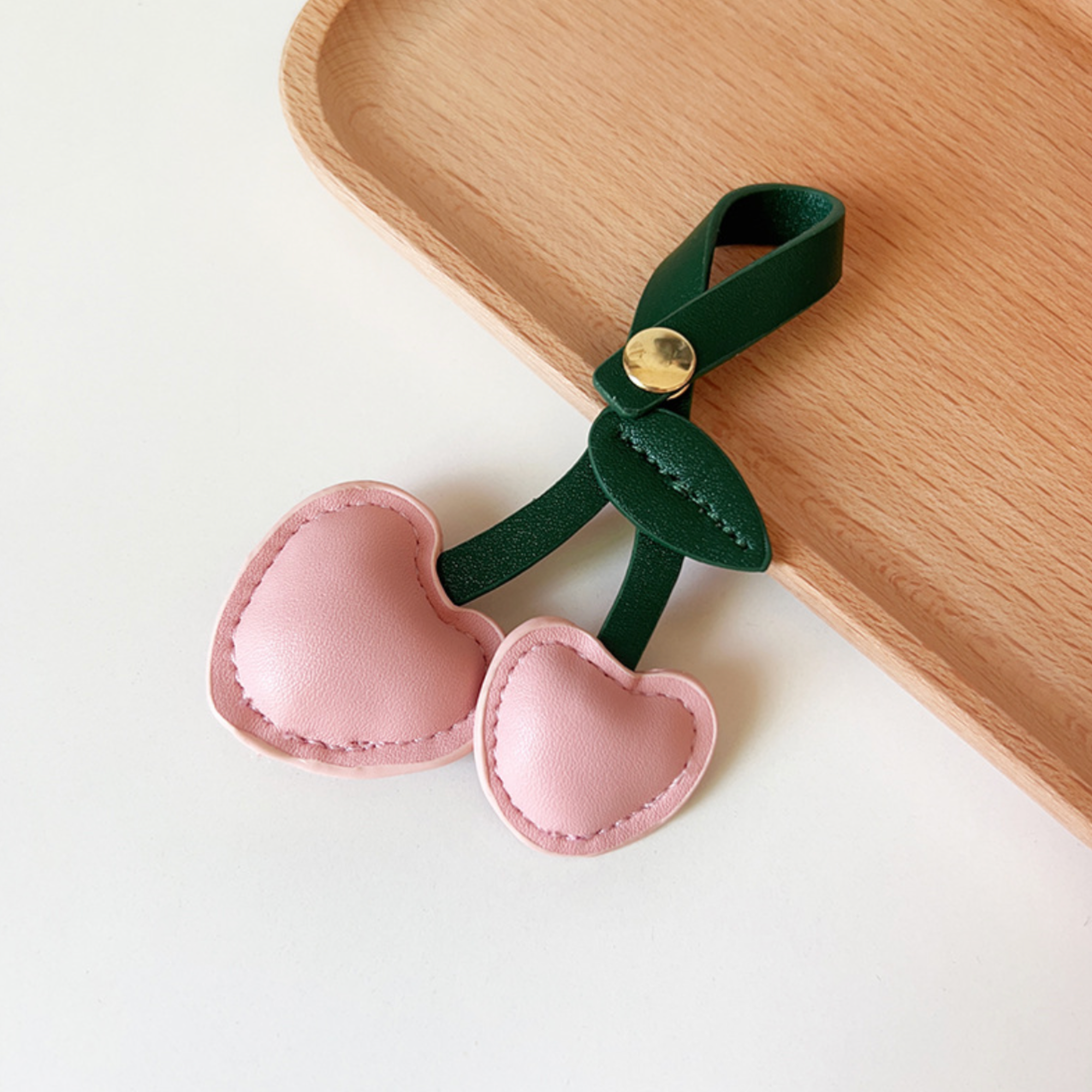 Two Pink leather heart shaped cherries with dark green leaf and looped stem and gold button clasp to use as bag charm