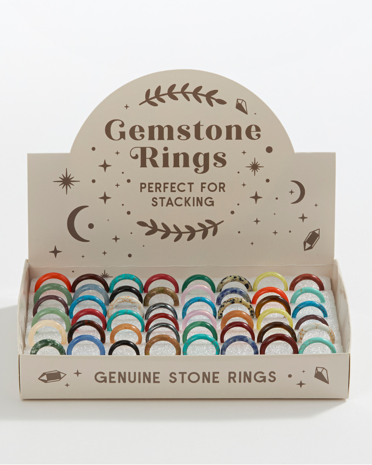 Box of gemstone rings with decorative text on a light gray background