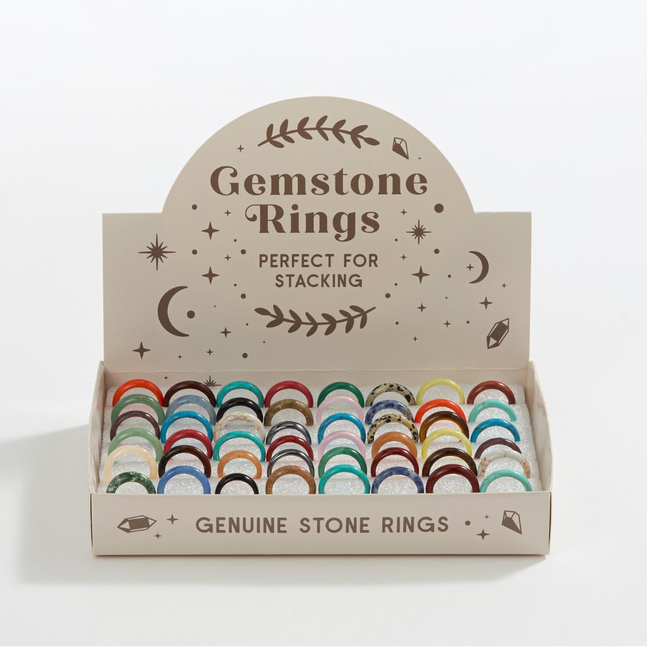 Box of gemstone rings with decorative text on a light gray background