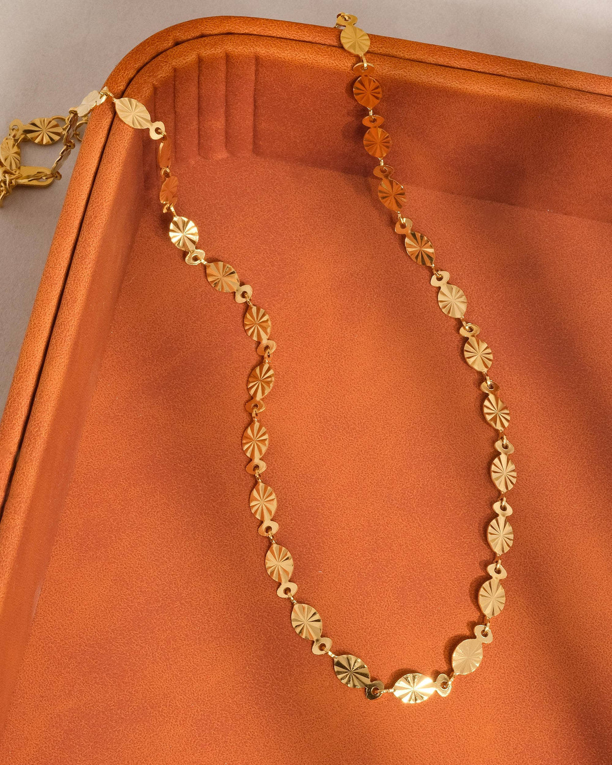 Gold necklace on an orange fabric background