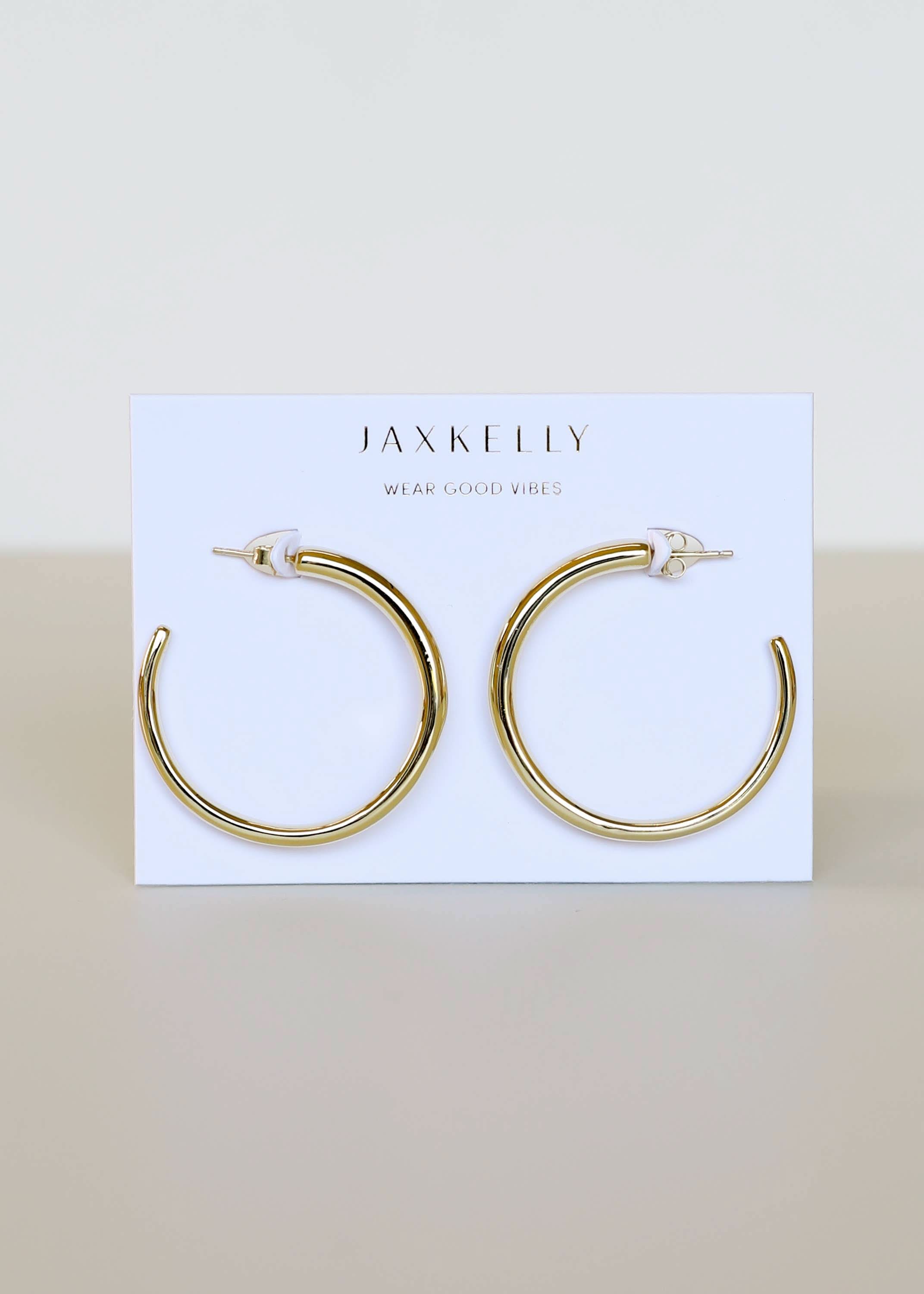 Gold hoop earrings on a Jax Kelley branded card with a beige background