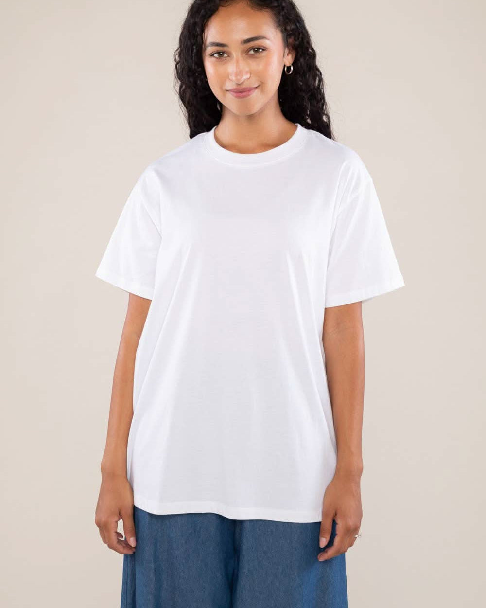 Woman wearing white boxy, oversized, shirt sleeved, tee t-shirt and jeans