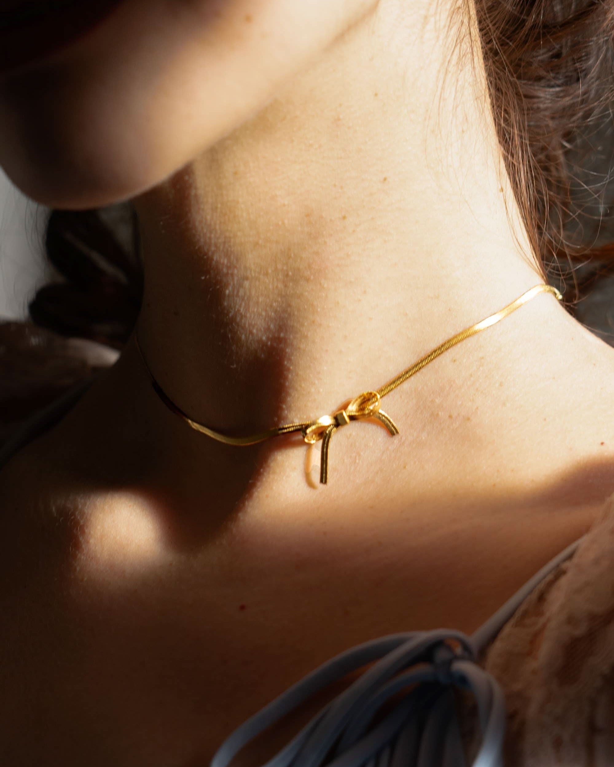woman wearing gold bow chocker necklace