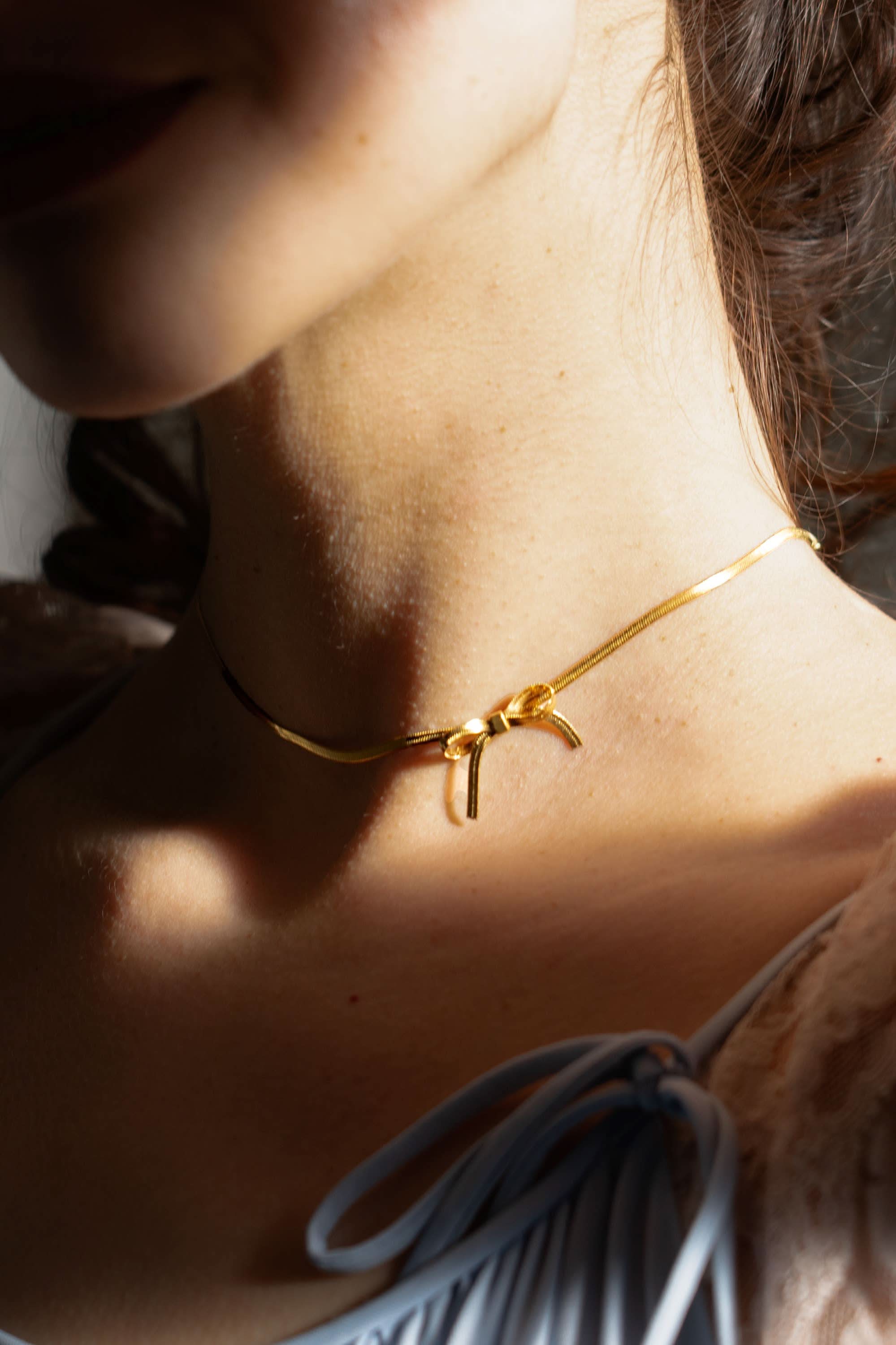 woman wearing gold bow chocker necklace
