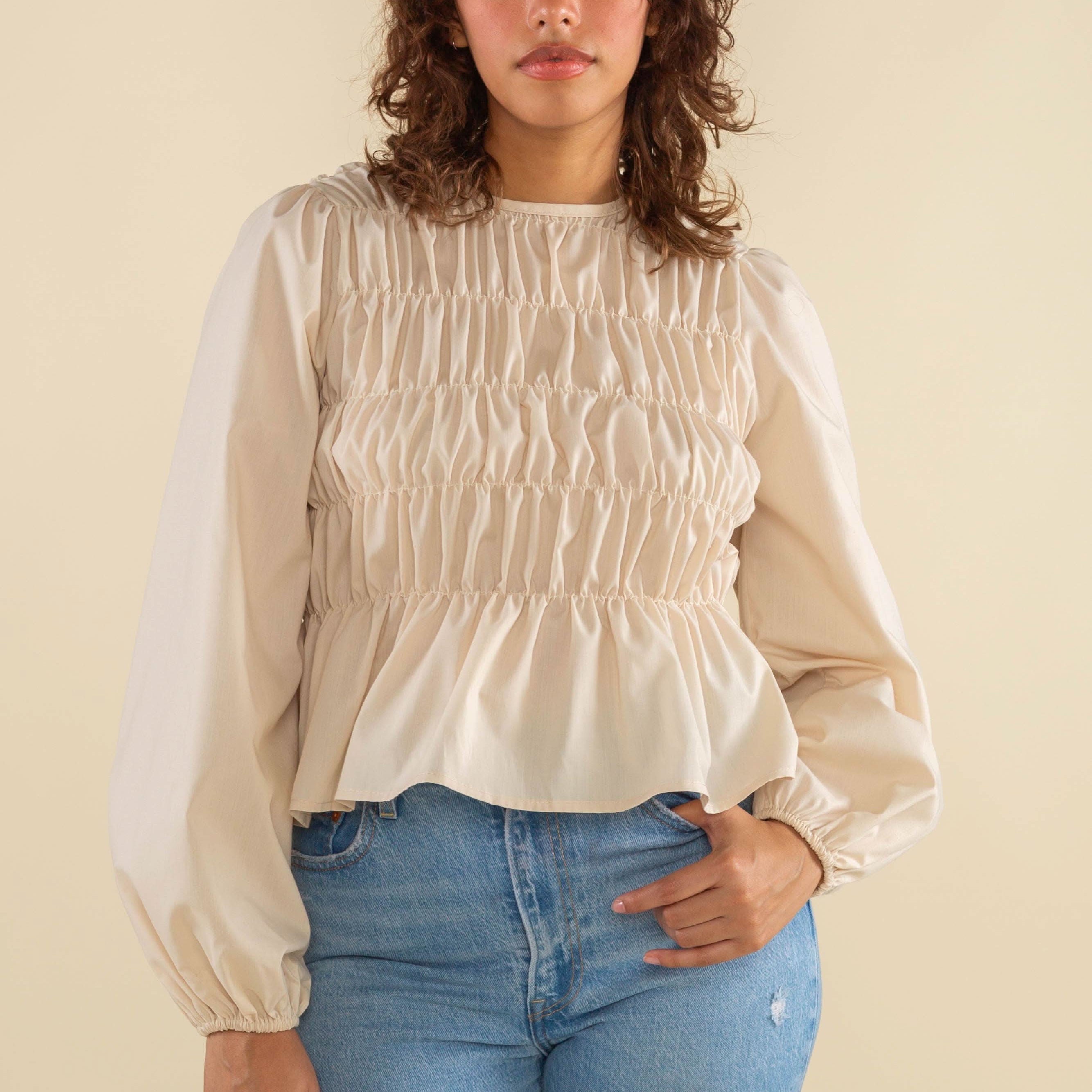 Woman wearing natural cream white color, bubble long sleeve, shirred, peplum style top