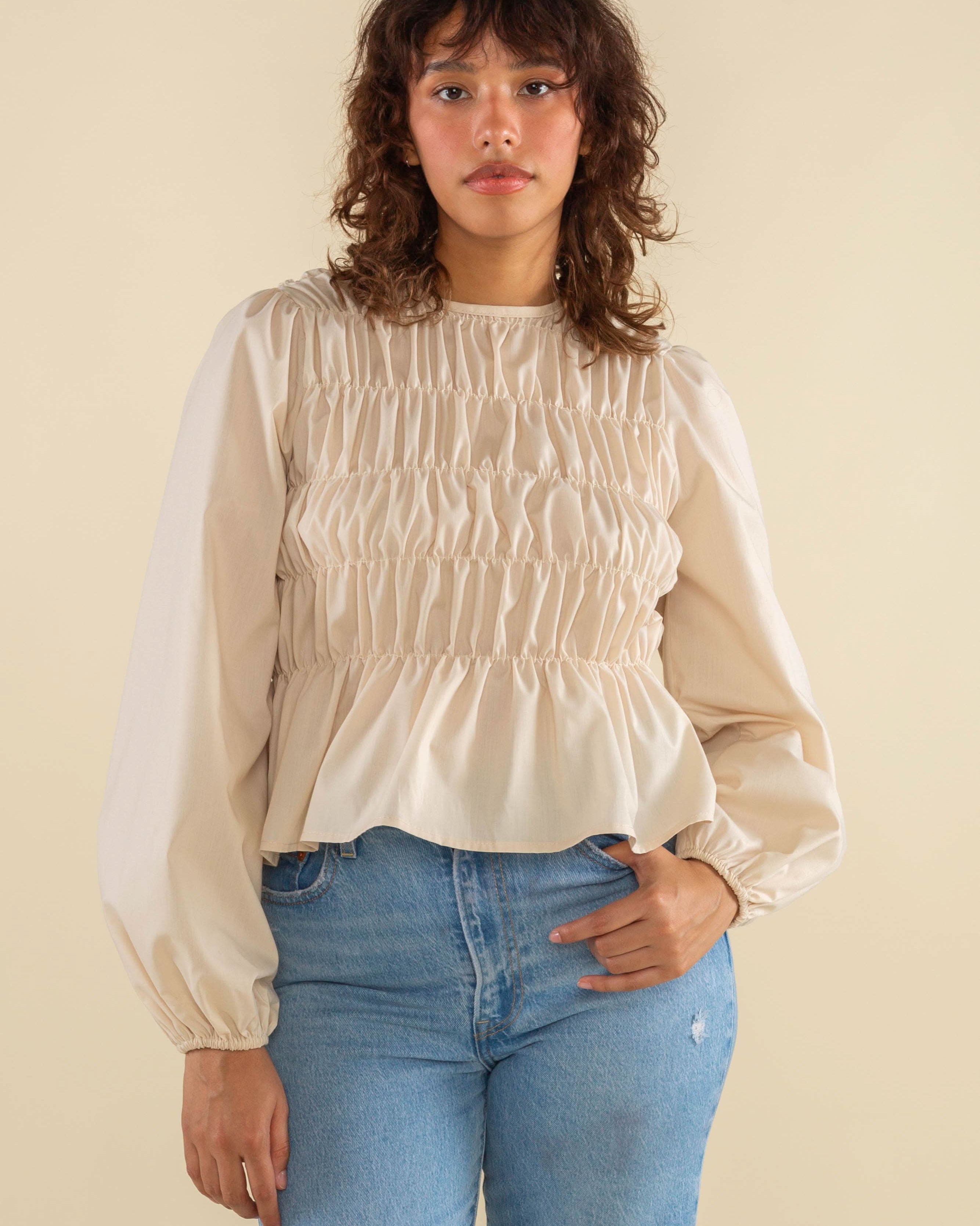 Woman wearing natural cream white color, bubble long sleeve, shirred, peplum style top
