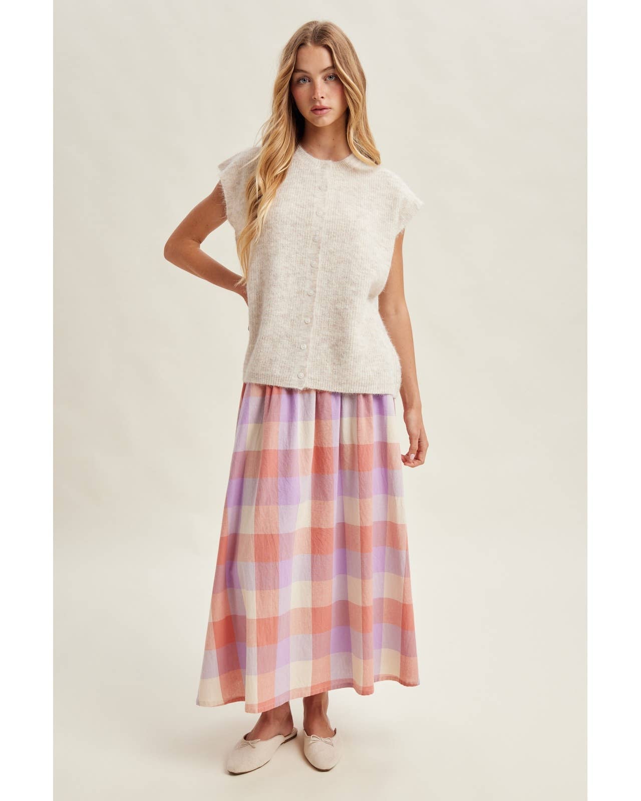 Woman wearing a white top and plaid skirt on a plain background