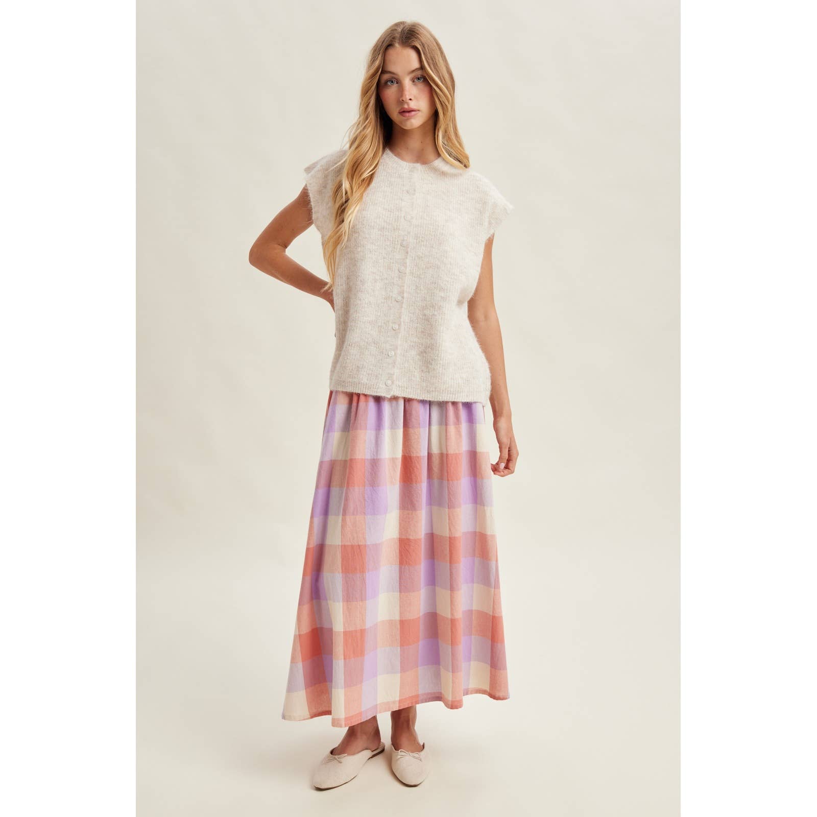 Woman wearing a white top and plaid skirt on a plain background