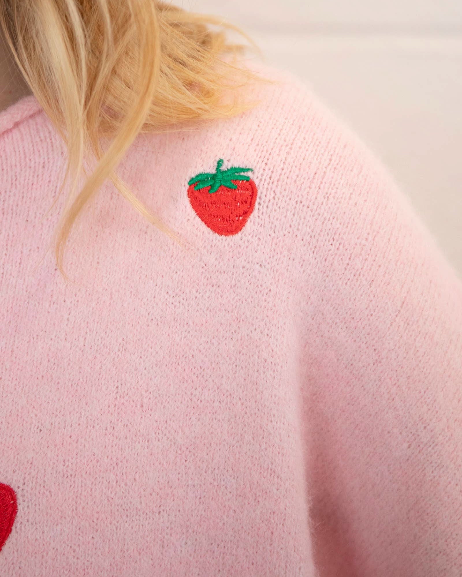 Woman wearing a pink button down cardigan with strawberries
