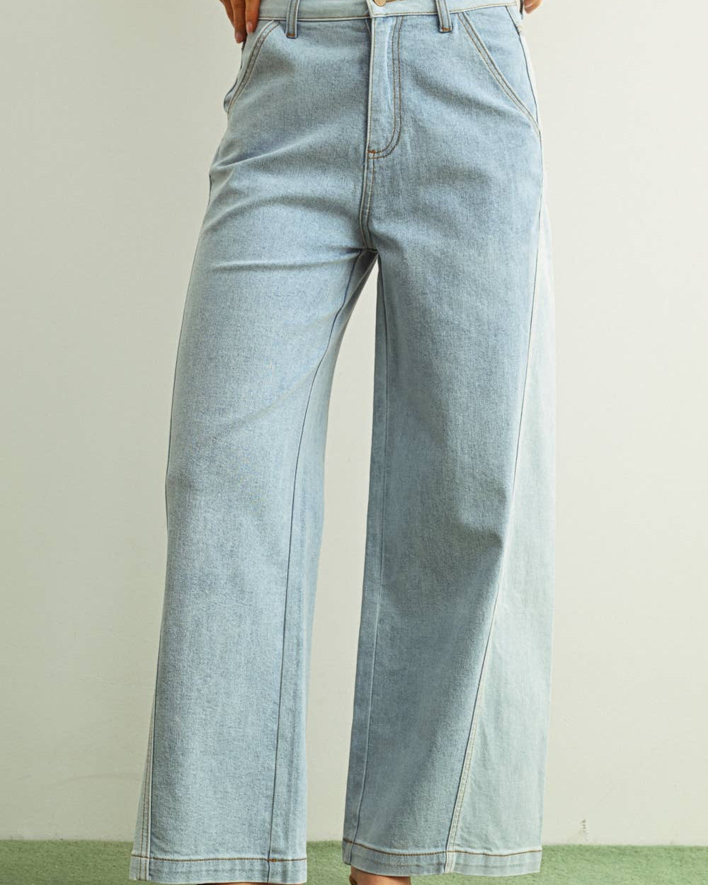 Woman wearing light denim jeans and light brown shoes standing behind a white background