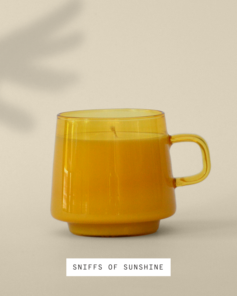 candle in Yellow opaque reusable mug sitting in the sun against a cream colored wall